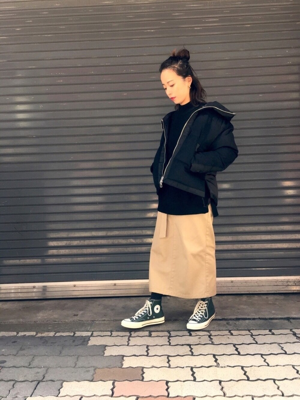 ブラック系のダウンジャケット/コート、ブラック系のニット/セーター、ベージュ系のスカートを着用したレディースの秋コーディネートの1枚目の写真