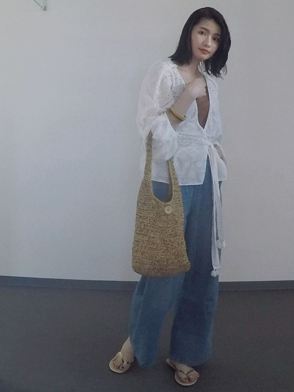 ホワイト系のトップス、ブルー系のデニムパンツを着用したレディースの夏コーディネートの1枚目の写真