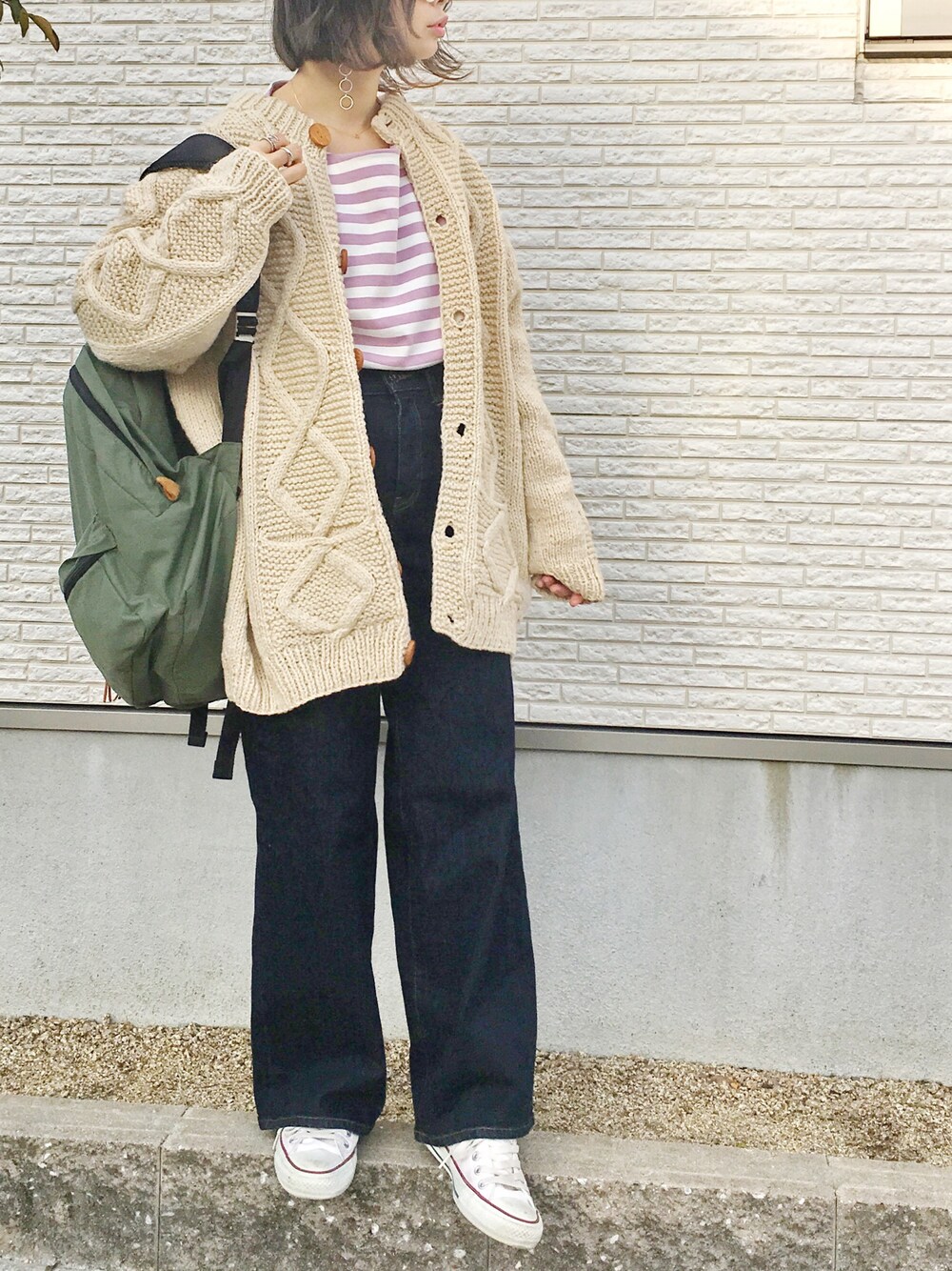 ピンク系のTシャツ/カットソー、ブルー系のデニムパンツ、グリーン系のバックパック/リュックを着用したレディースの冬コーディネートの1枚目の写真