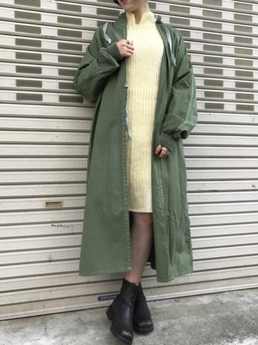 イエロー系のワンピース、ブラウン系のブーツを着用したレディースの冬コーディネートの1枚目の写真