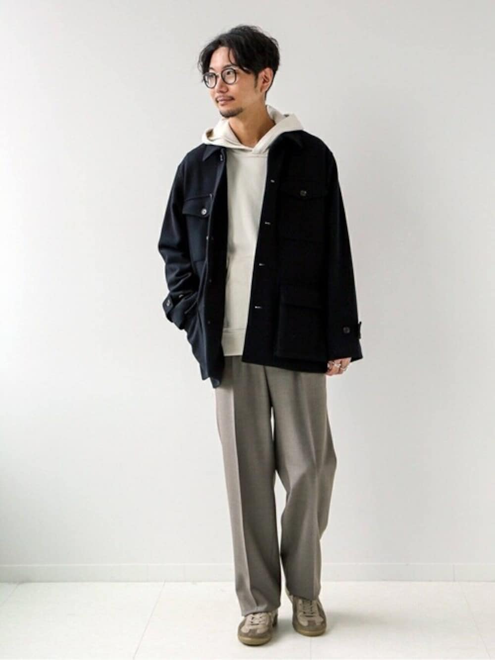 ブラック系のミリタリージャケット、ホワイト系のニット/セーター、ベージュ系のスニーカーを着用したメンズの冬コーディネートの1枚目の写真