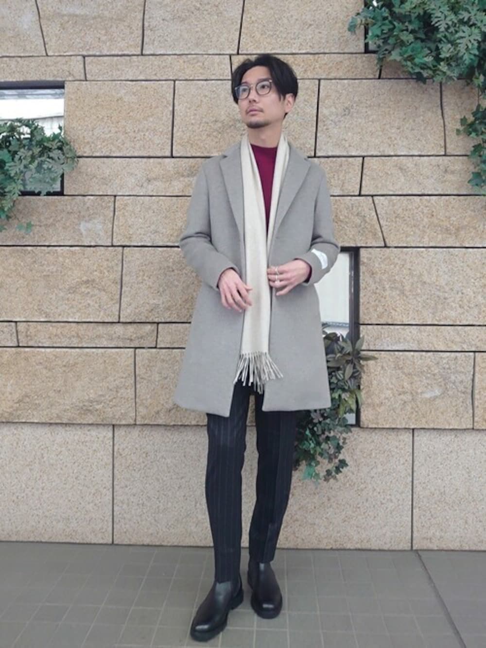 グレー系のチェスターコート、レッド系のニット/セーター、ブラック系のその他パンツを着用したメンズの冬コーディネートの1枚目の写真