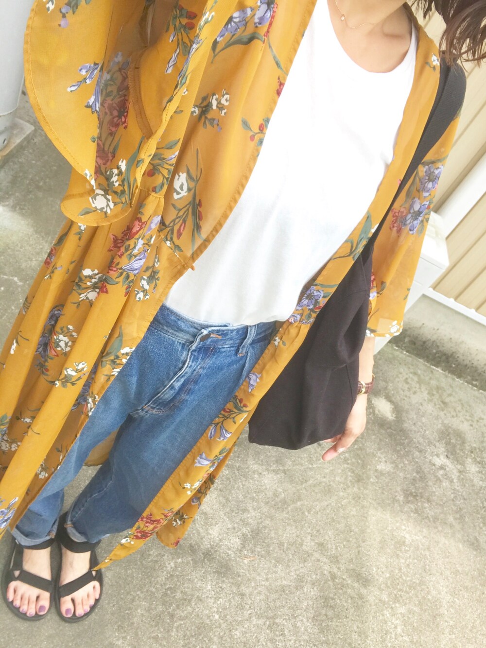 イエロー系のワンピース、ブルー系のデニムパンツ、ブラック系のサンダルを着用したレディースの夏コーディネートの1枚目の写真