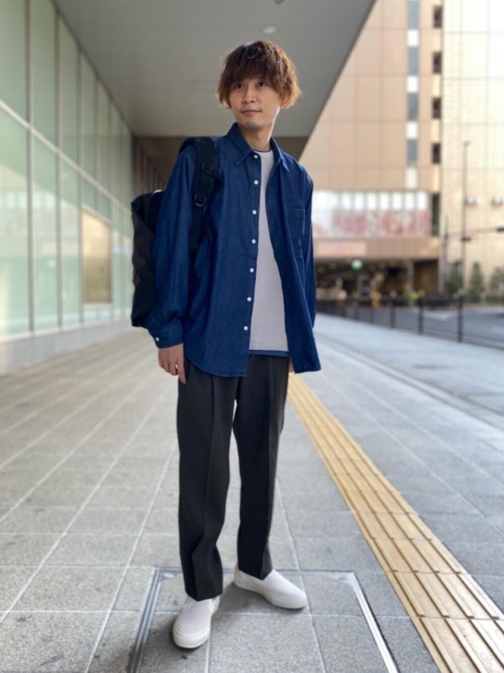 ホワイト系のスニーカー、ブラック系のバックパック/リュック、ブルー系のシャツ/ブラウスを着用したメンズの夏コーディネートの1枚目の写真