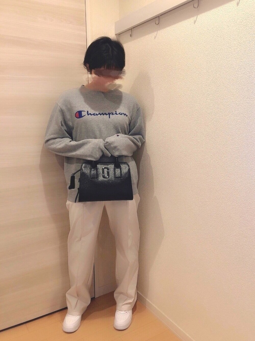 グレー系のスウェット、ブラック系のトートバッグ、ホワイト系のスラックスを着用したレディースの冬コーディネートの1枚目の写真