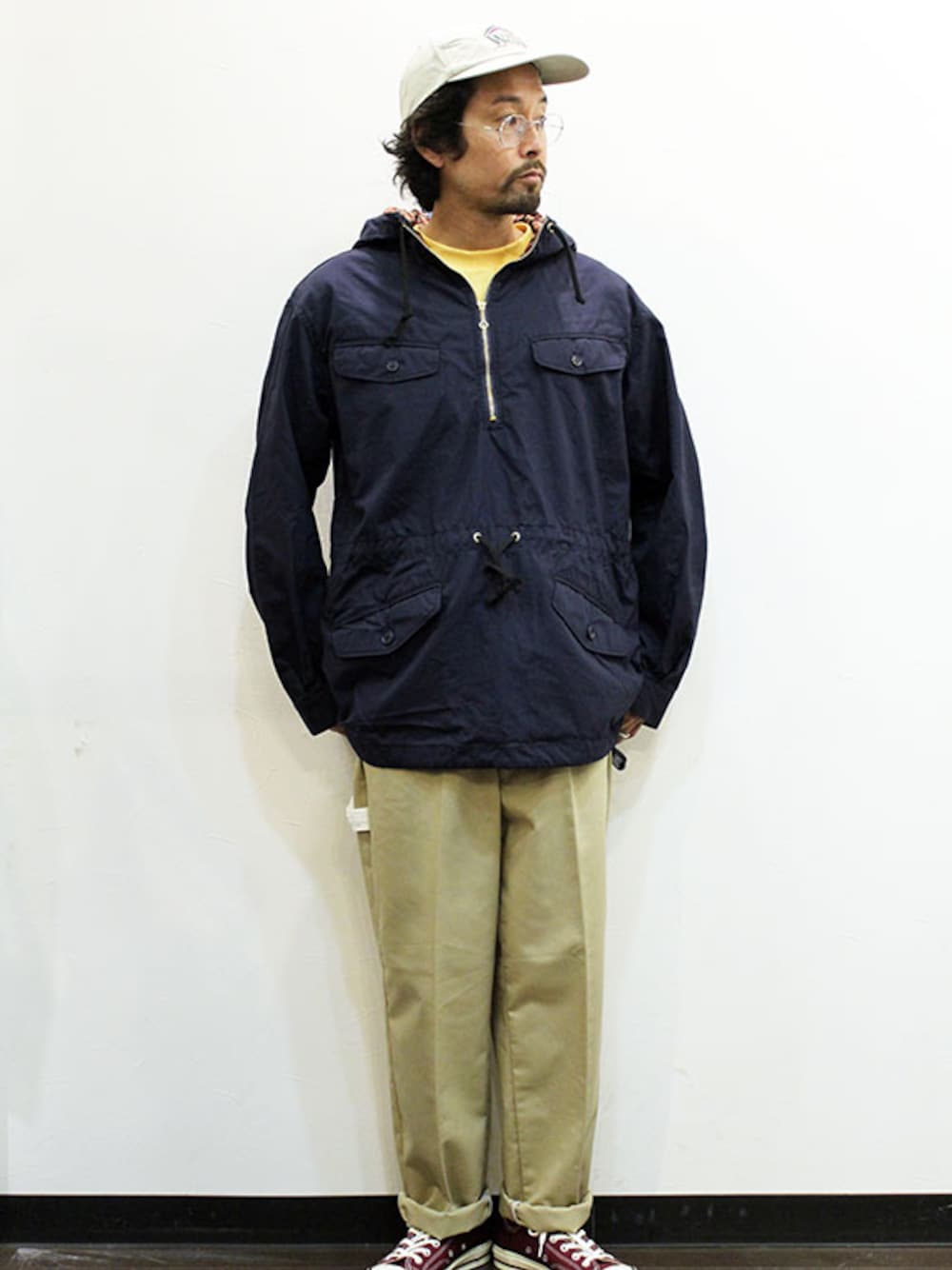 ブルー系のマウンテンパーカー、オレンジ系のTシャツ/カットソー、ベージュ系のチノパンツを着用したメンズの春コーディネートの1枚目の写真