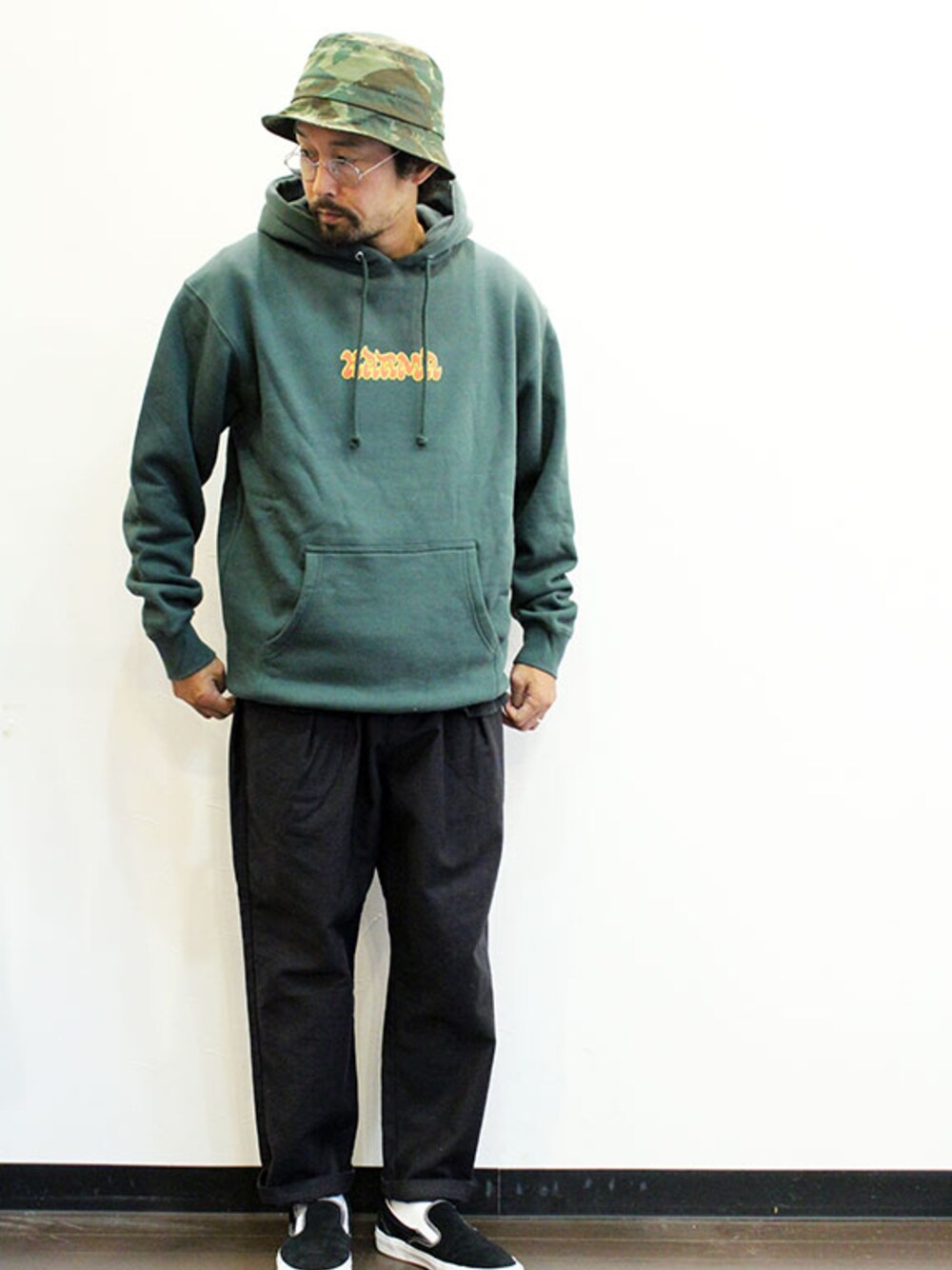 ブラック系のチノパンツ、グリーン系のパーカー、ブラック系のスニーカーを着用したメンズの秋コーディネートの1枚目の写真