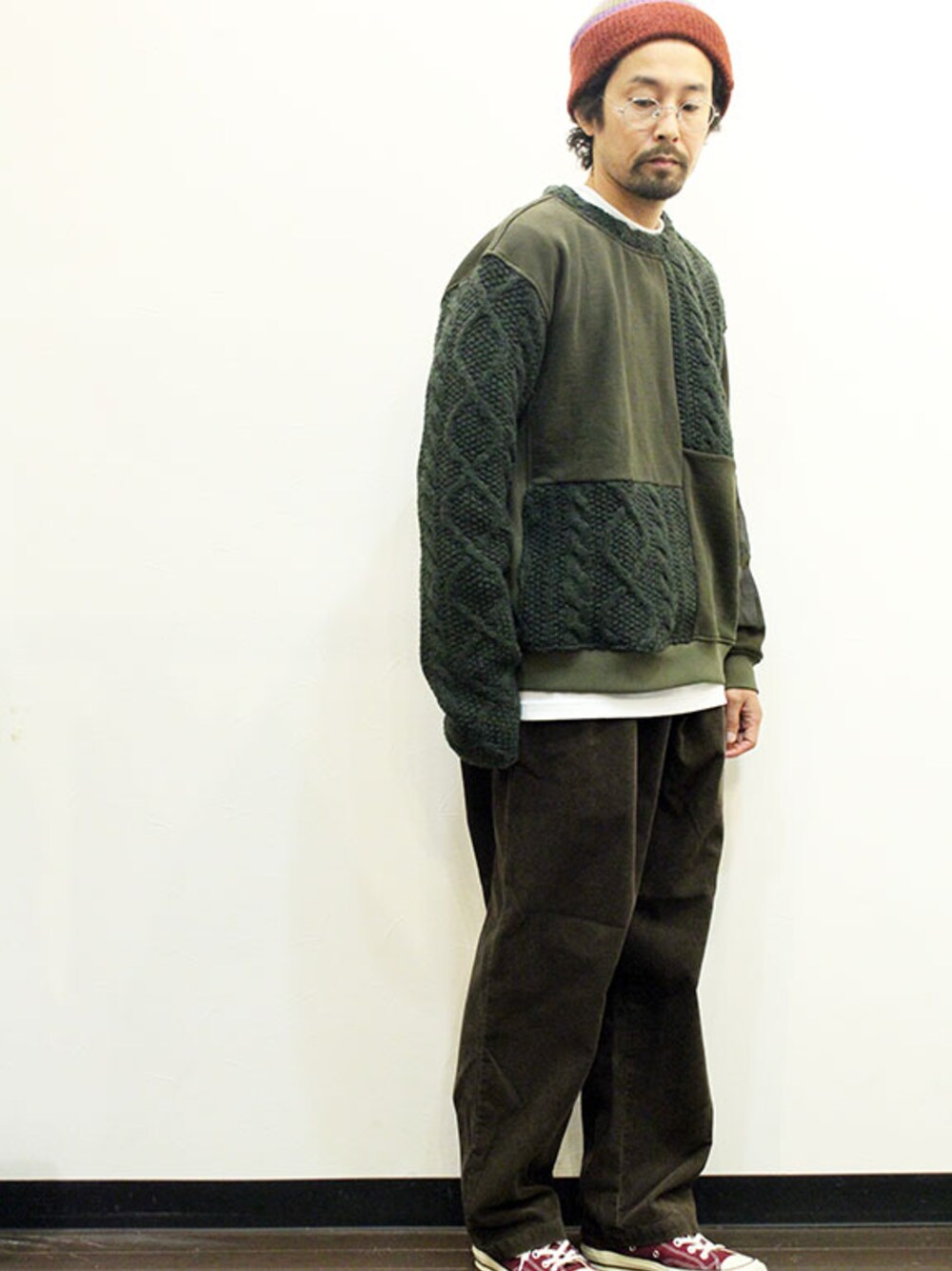 グリーン系のニット/セーター、ブラウン系のスラックス、グリーン系のスニーカーを着用したメンズの冬コーディネートの1枚目の写真