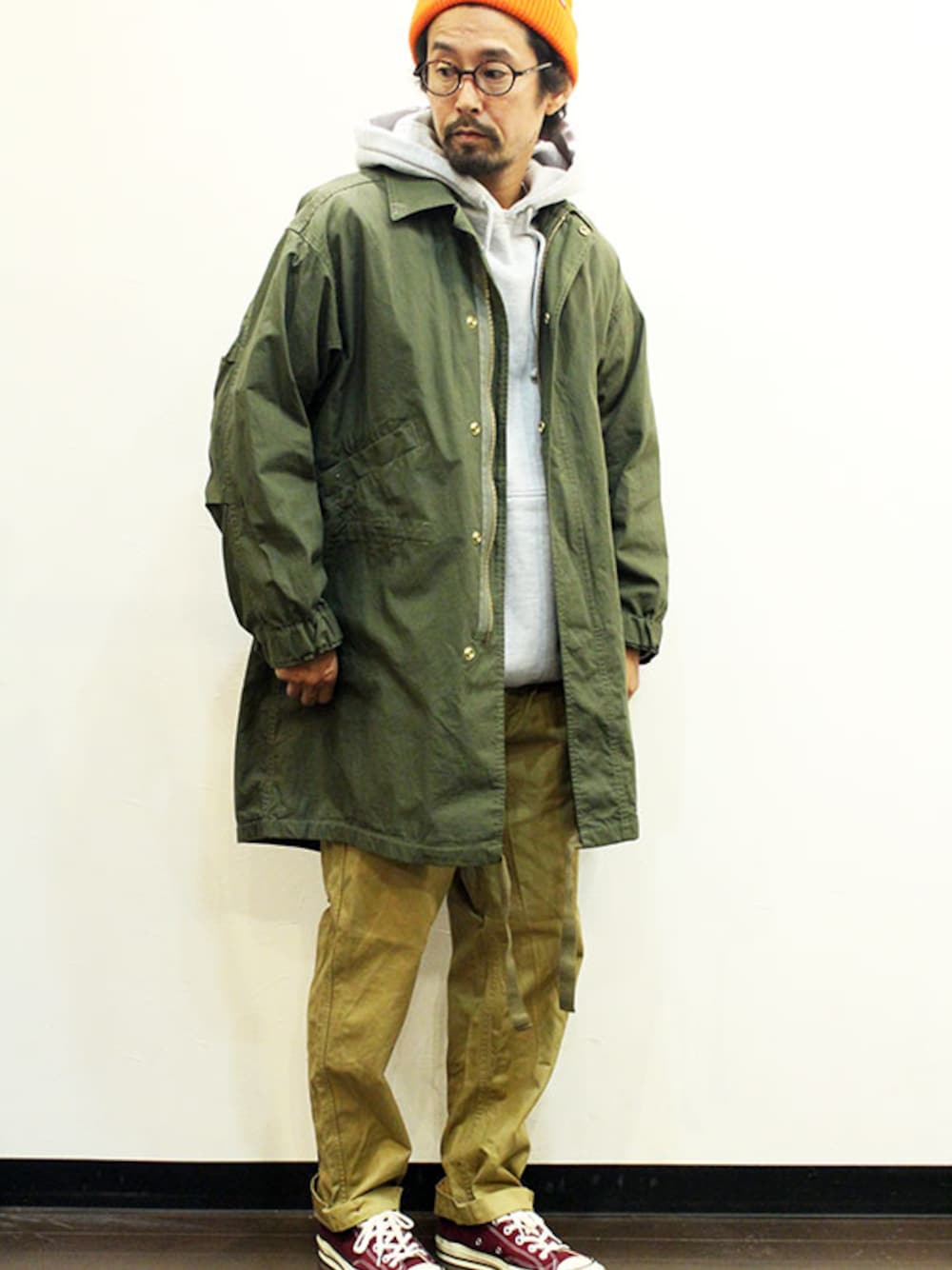 グリーン系のモッズコート、グレー系のパーカー、ベージュ系のチノパンツを着用したメンズの冬コーディネートの1枚目の写真