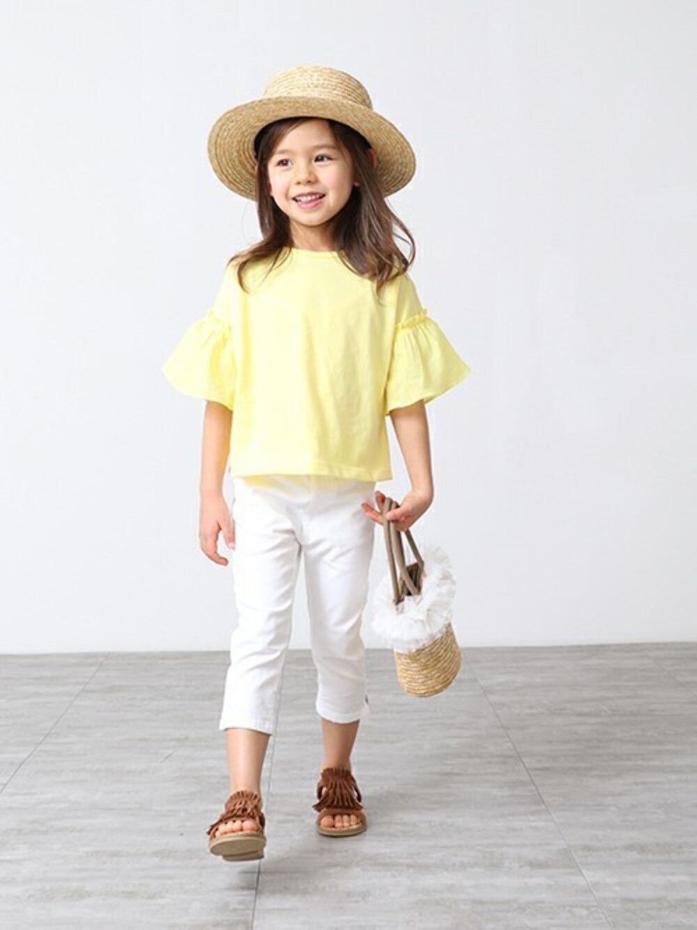 イエロー系のTシャツ/カットソー、ホワイト系のその他パンツ、ブラウン系のサンダルを着用したキッズの春コーディネートの1枚目の写真