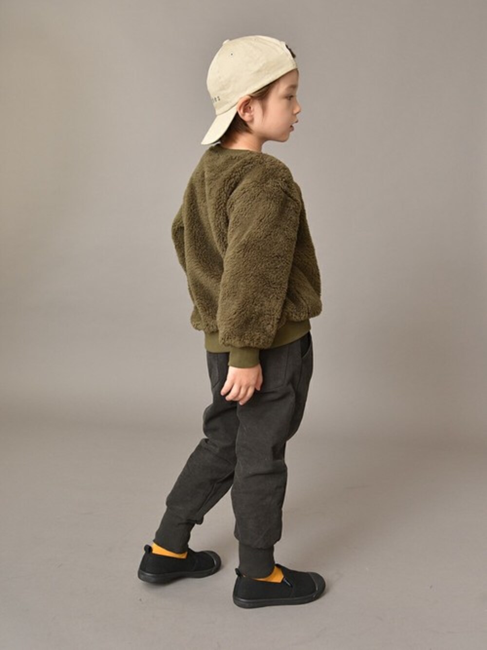 グリーン系のスウェット、ブラック系のスリッポン、ベージュ系のキャップを着用したキッズの秋コーディネートの1枚目の写真