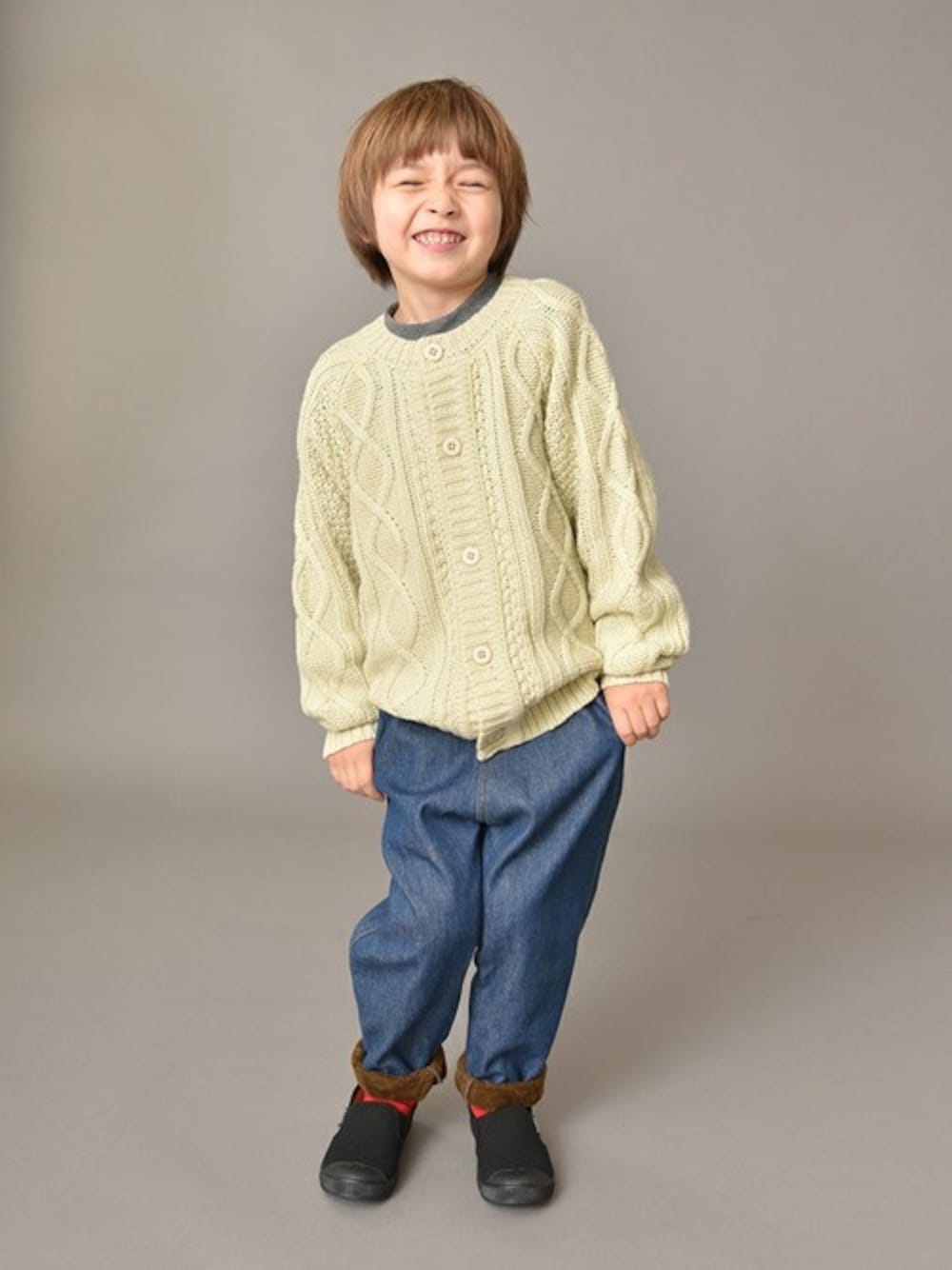 ホワイト系のカーディガン/ボレロ、グレー系のTシャツ/カットソー、ブルー系のデニムパンツを着用したキッズの冬コーディネートの1枚目の写真