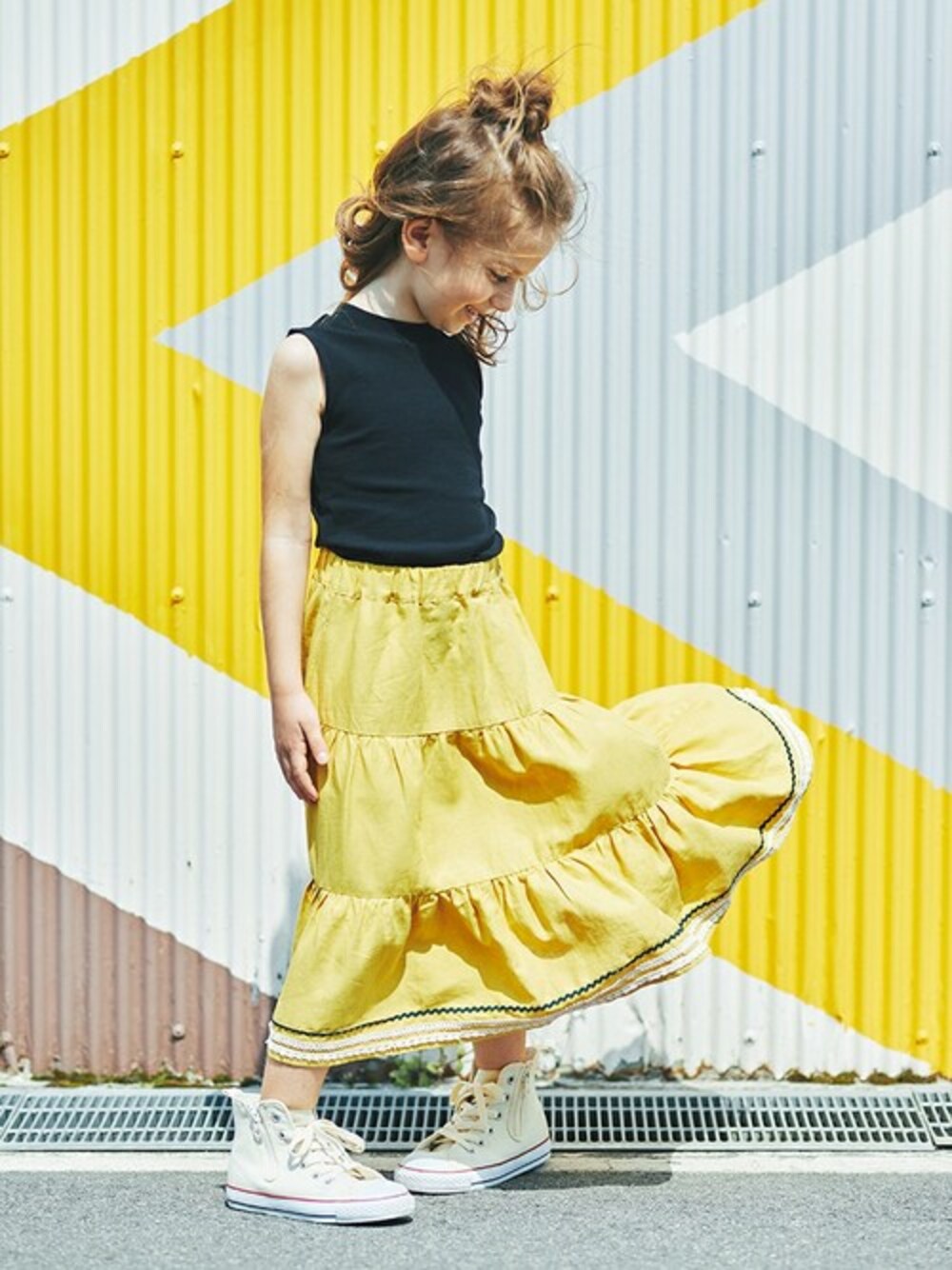 ブラック系のタンクトップ、イエロー系のスカートを着用したキッズの夏コーディネートの1枚目の写真