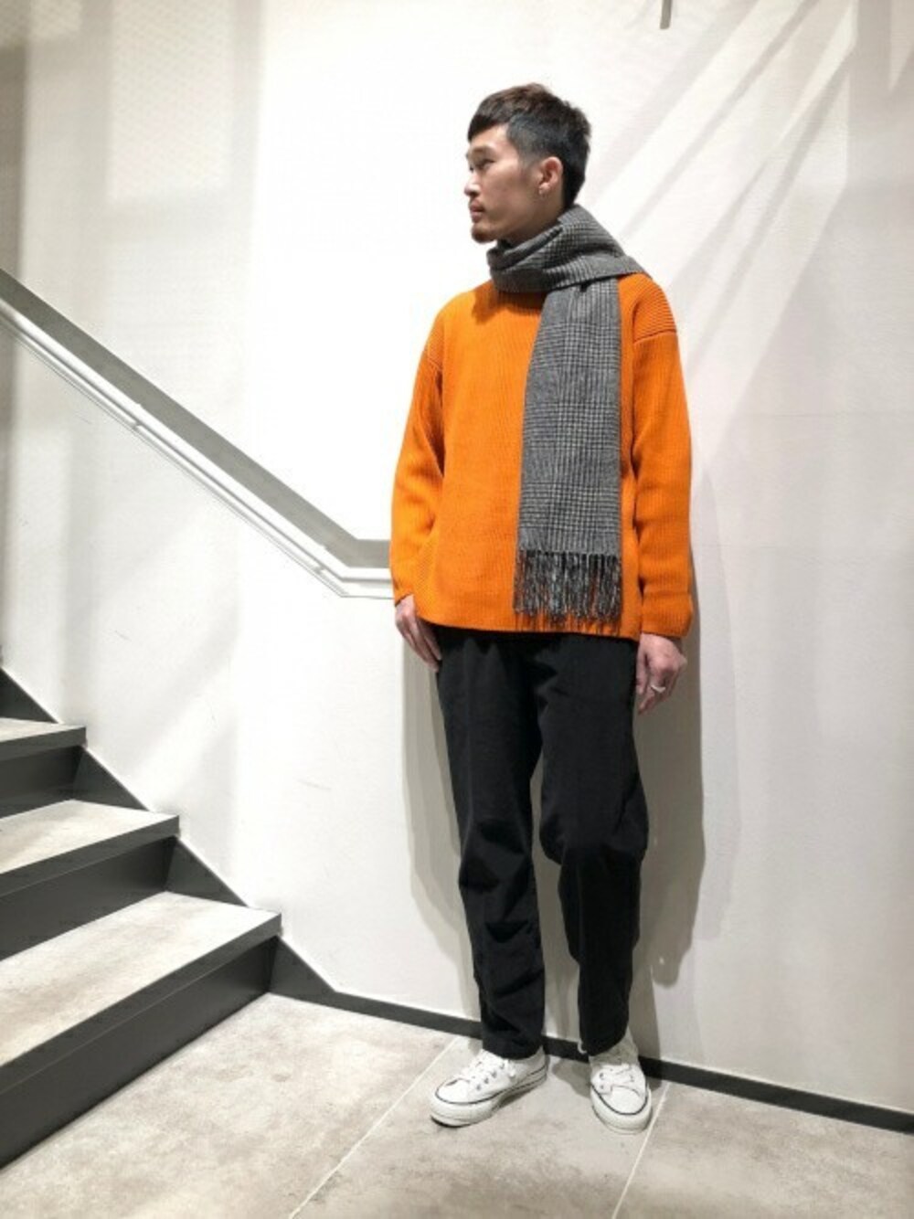 オレンジ系のニット/セーター、ブラック系のその他パンツ、ホワイト系のスニーカーを着用したメンズの秋コーディネートの1枚目の写真