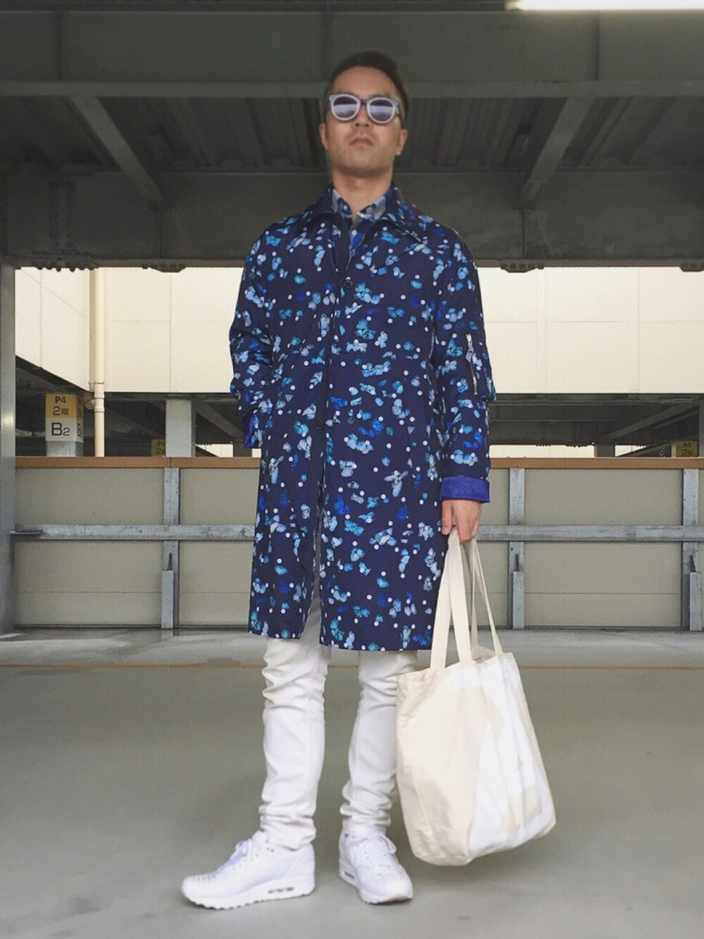 ブルー系のステンカラーコート、ホワイト系のデニムパンツ、ホワイト系のトートバッグを着用したメンズの秋コーディネートの1枚目の写真