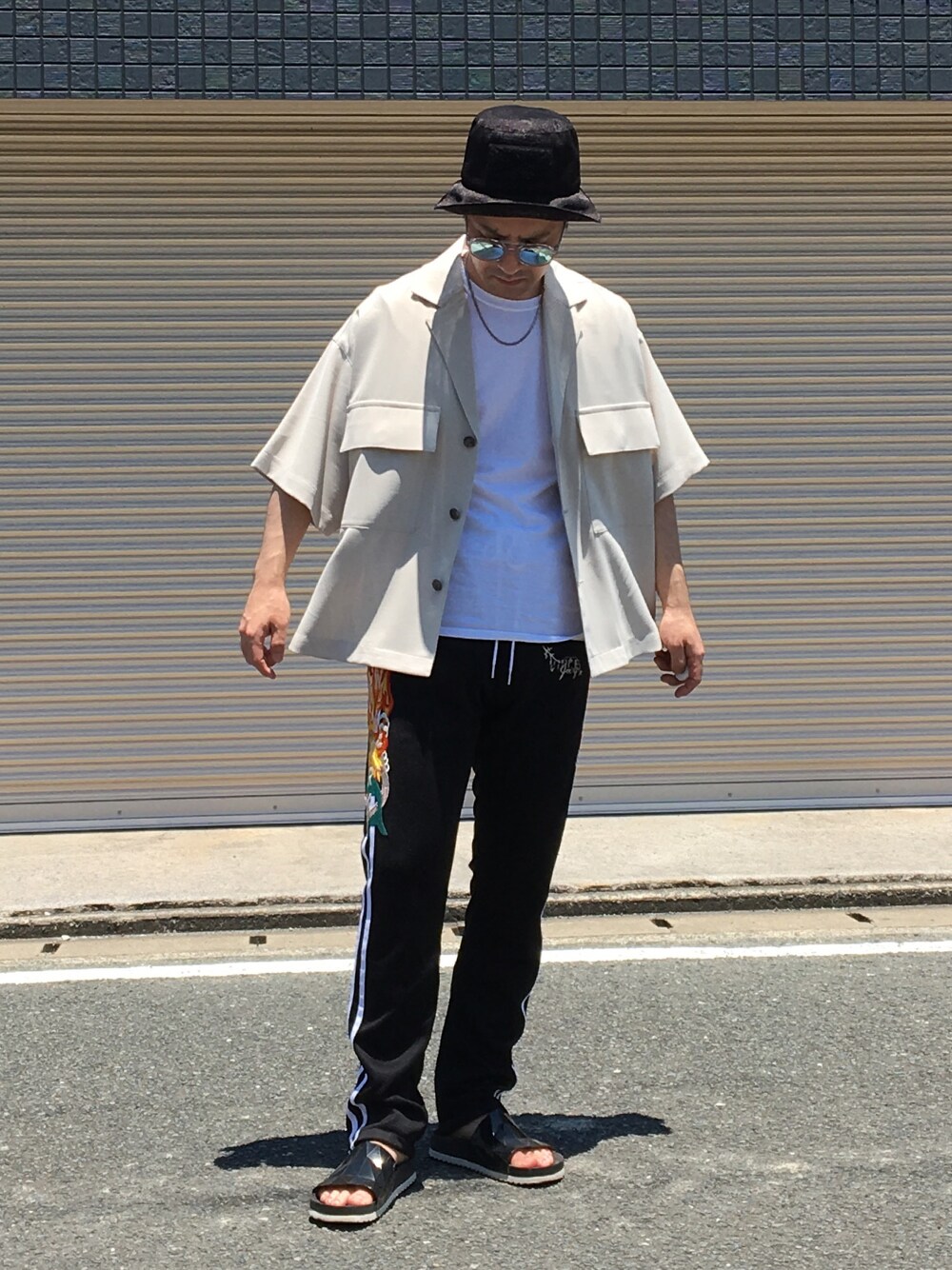 ブラック系のパンツ、ブラック系のサンダル、グレー系のシャツ/ブラウスを着用したメンズの夏コーディネートの1枚目の写真