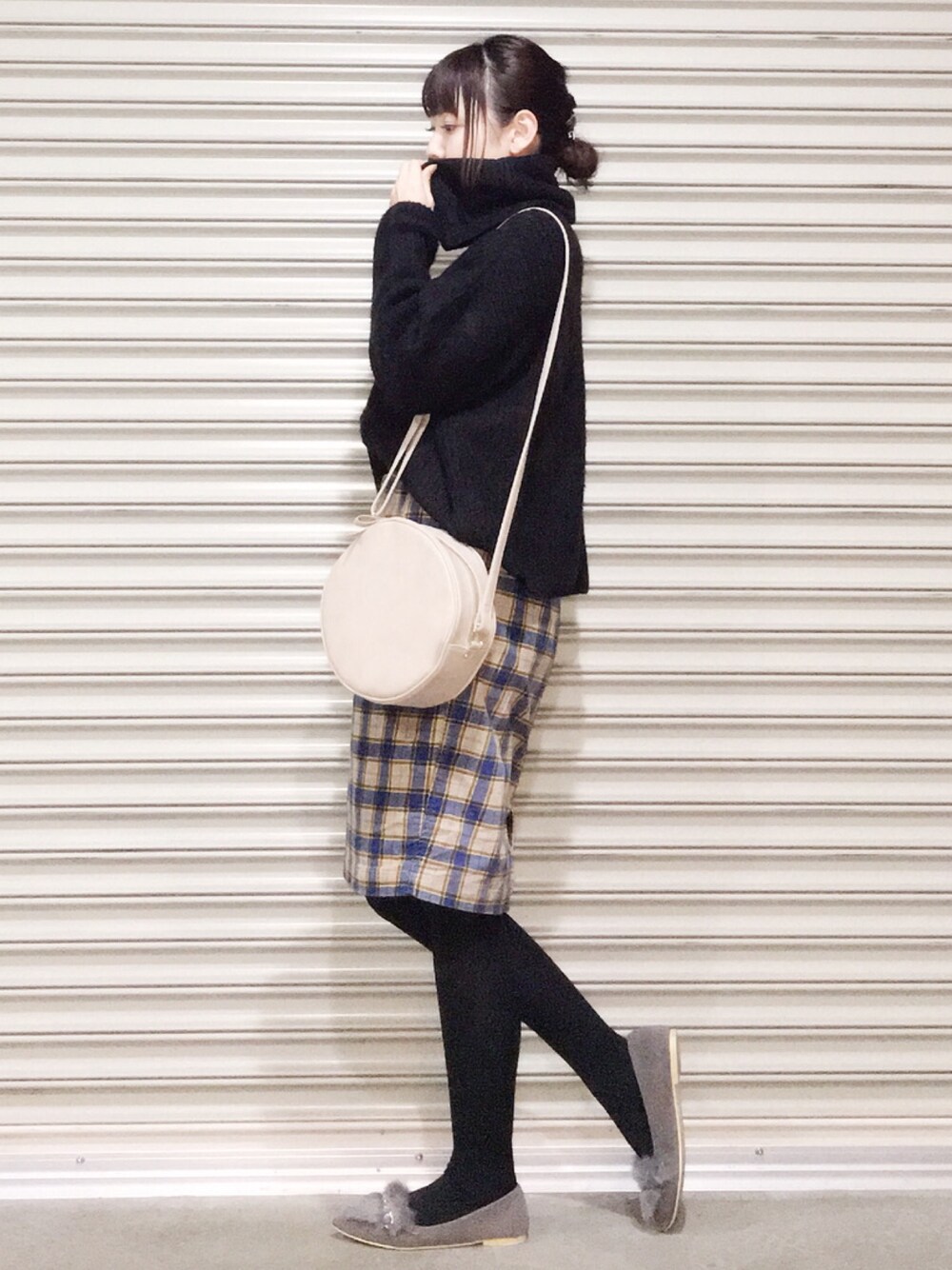 ブラック系のニット/セーター、ブルー系のスカート、ベージュ系のショルダーバッグを着用したレディースの冬コーディネートの1枚目の写真