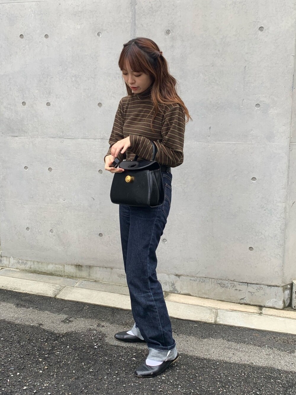 ブルー系のデニムパンツ、ブラック系のパンプスを着用したレディースの秋コーディネートの1枚目の写真