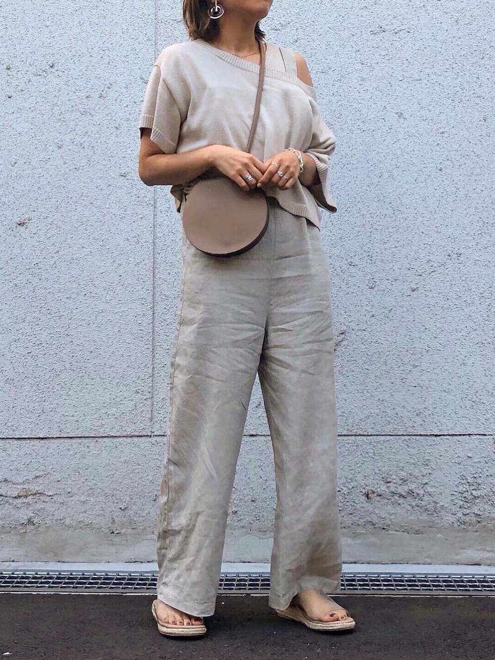 ベージュ系のニット/セーター、ベージュ系のサロペット/オーバーオール、イエロー系のショルダーバッグを着用したレディースの夏コーディネートの1枚目の写真