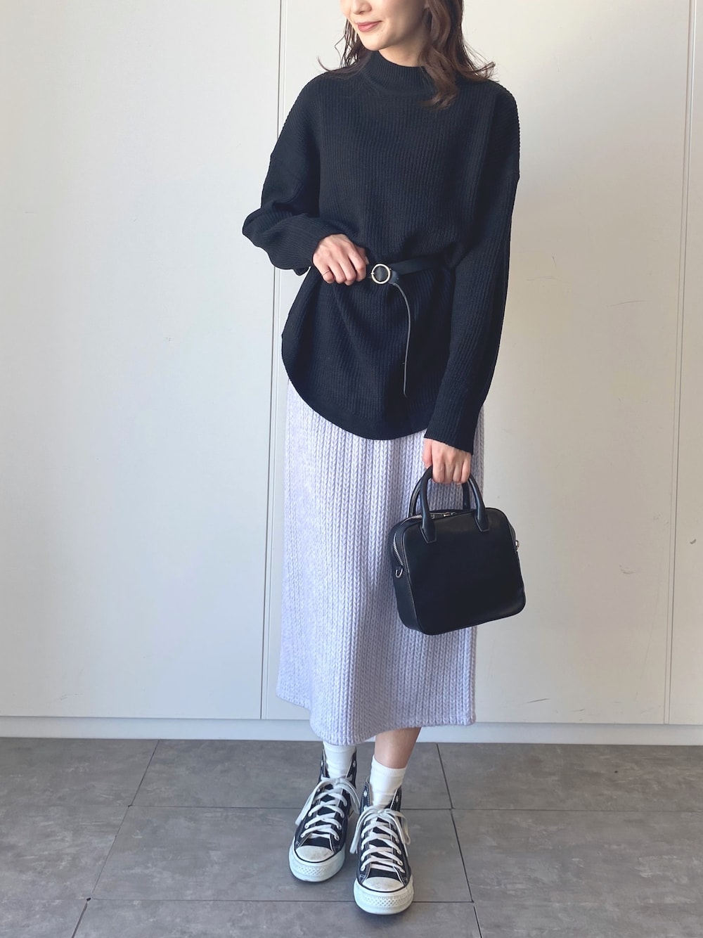 ブラック系のニット/セーター、パープル系のスカートを着用したレディースの冬コーディネートの1枚目の写真