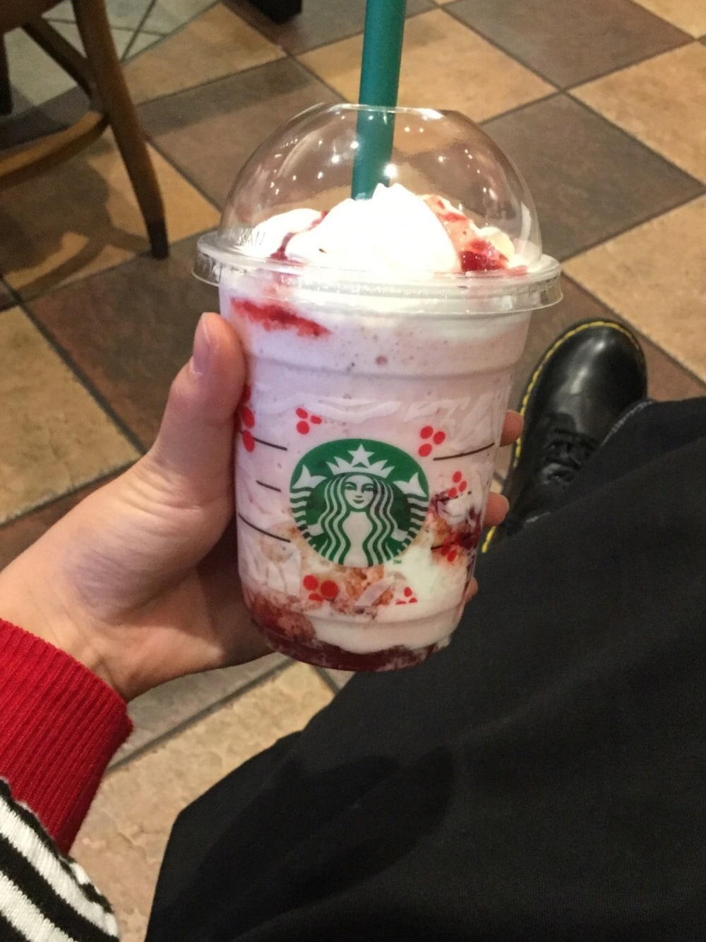 レッド系のニット/セーター、ブラック系のスカート、ブラック系のブーツを着用したレディースの秋コーディネートの1枚目の写真