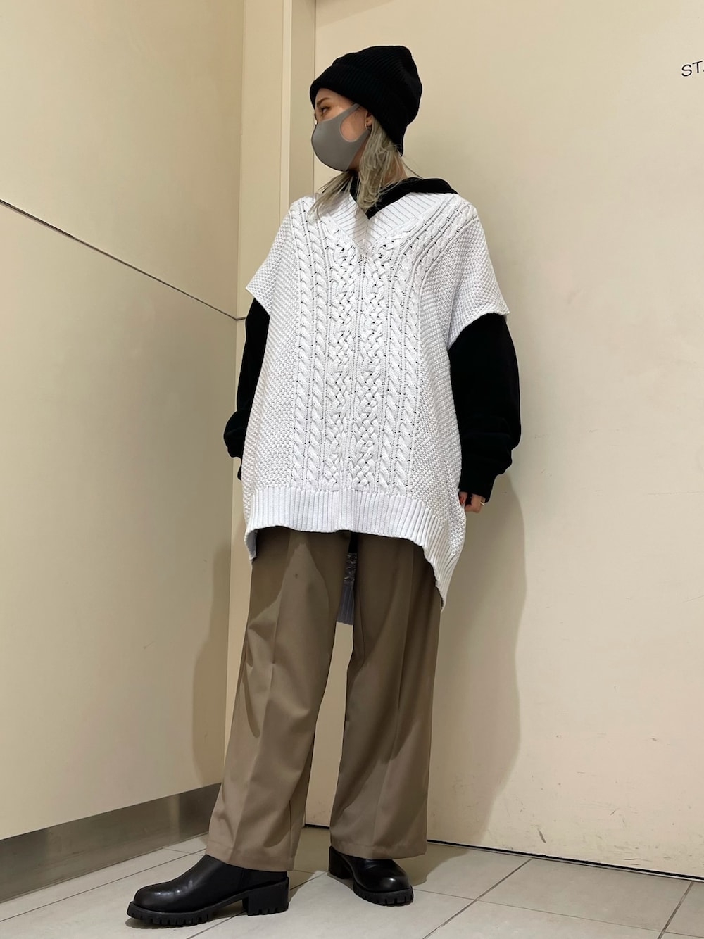 ホワイト系のベスト、ブラック系のパーカー、ベージュ系のスラックスを着用したレディースの冬コーディネートの1枚目の写真