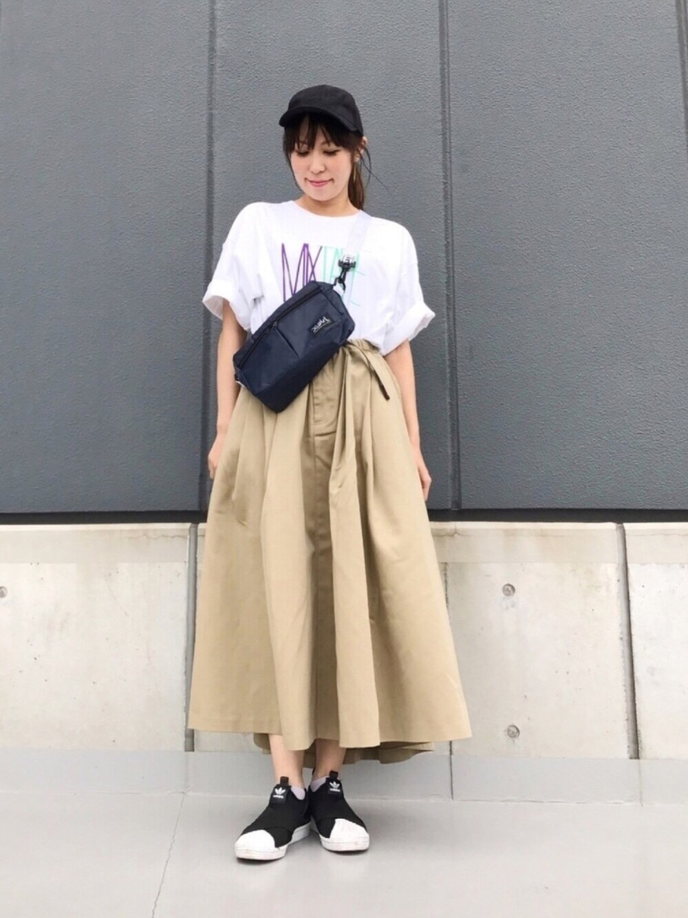 ホワイト系のTシャツ/カットソー、ベージュ系のスカート、ブラック系のスリッポンを着用したレディースの夏コーディネートの1枚目の写真