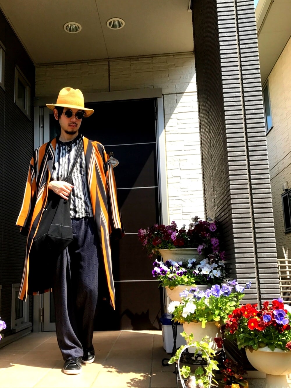 グレー系のトップス、オレンジ系のその他アウター、ブラック系のトートバッグを着用したメンズの春コーディネートの1枚目の写真