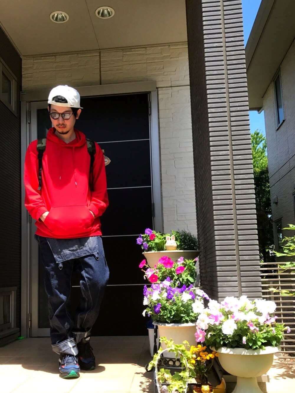 レッド系のパーカー、グレー系のデニムパンツ、その他のスニーカーを着用したメンズの夏コーディネートの1枚目の写真