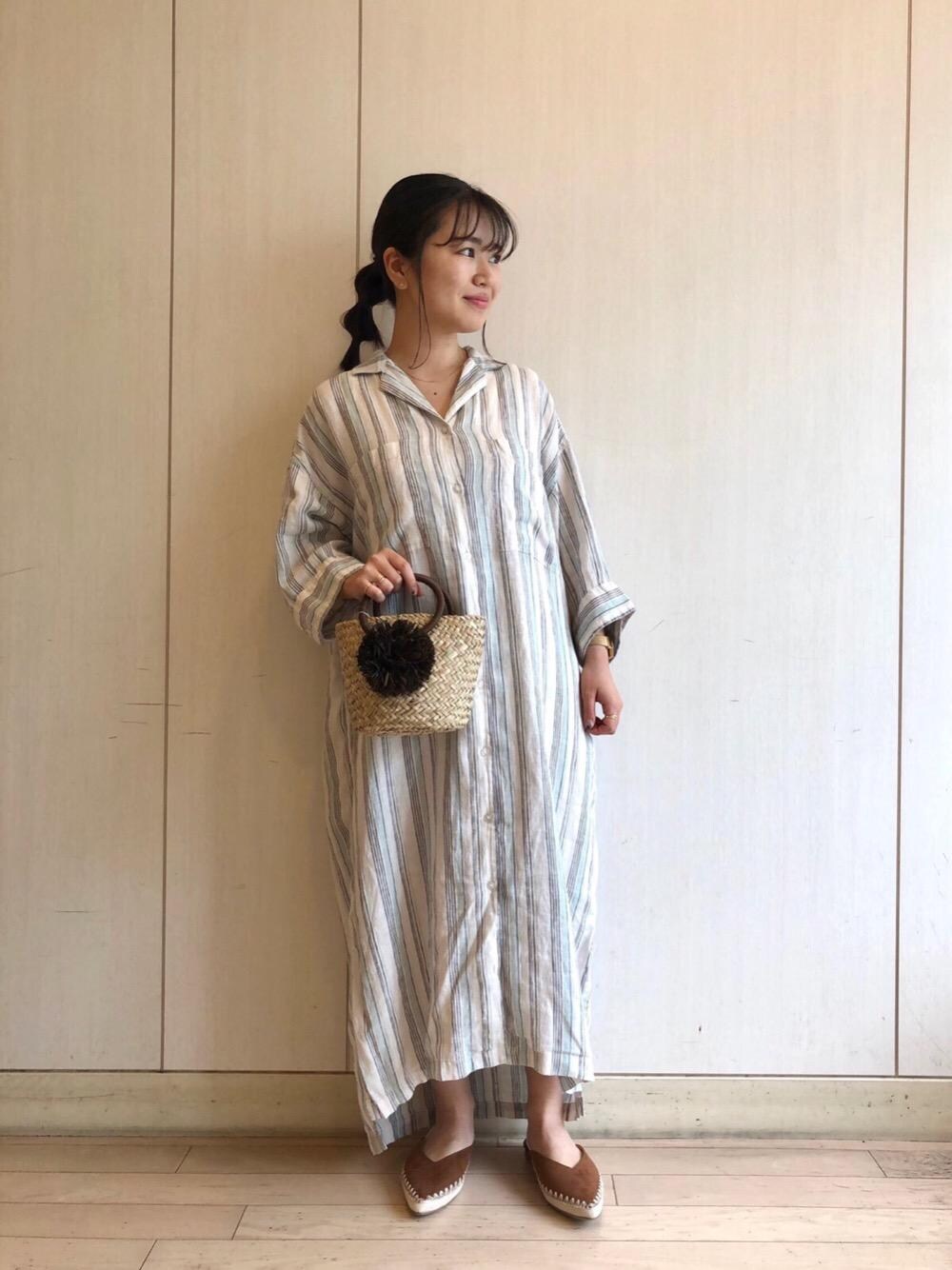 グリーン系のシャツワンピース、ブラウン系のサンダル、ブラウン系のかごバッグを着用したレディースの夏コーディネートの1枚目の写真