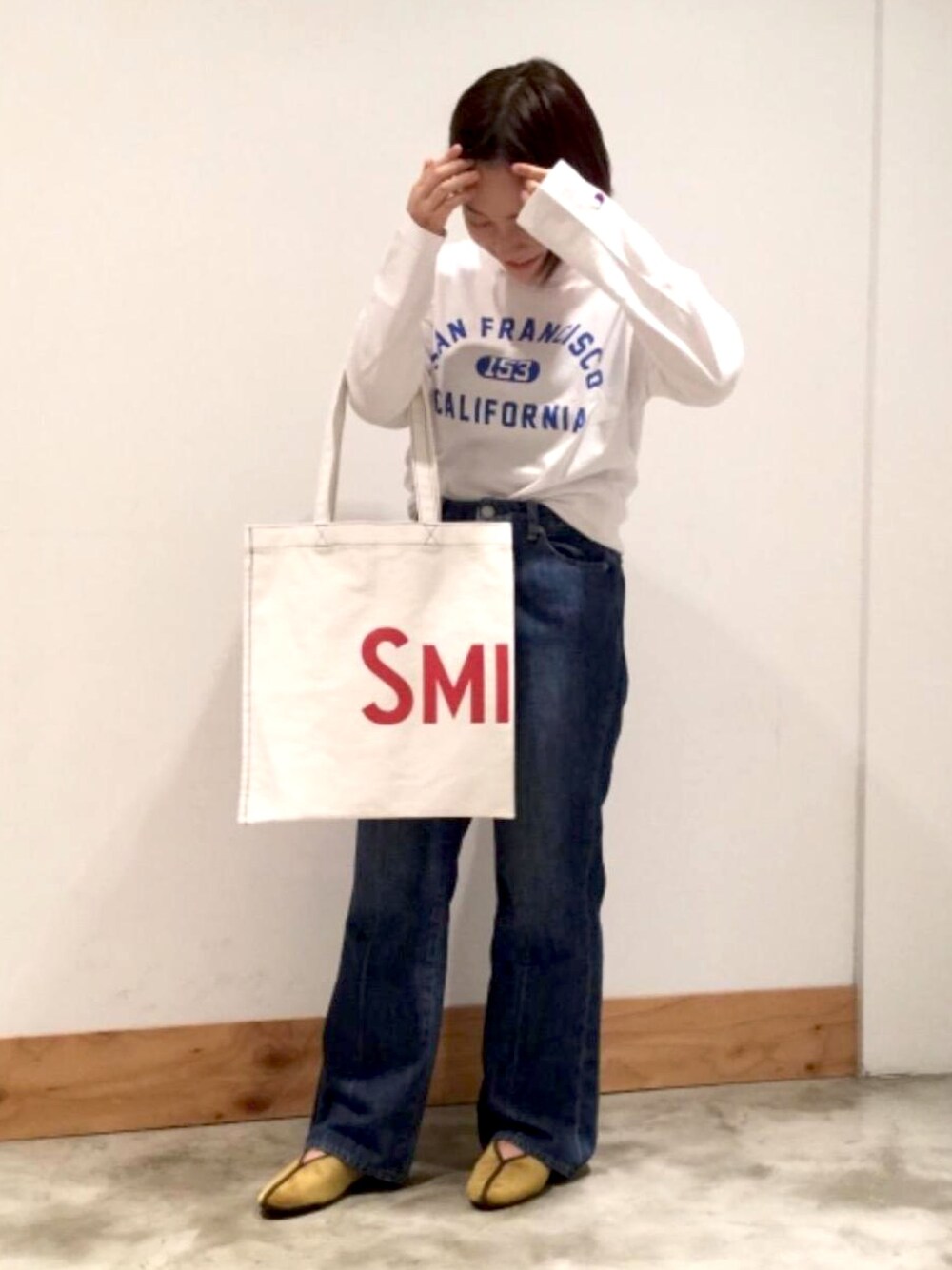 イエロー系のスリッポン、ブルー系のデニムパンツ、ホワイト系のトートバッグを着用したレディースの夏コーディネートの1枚目の写真