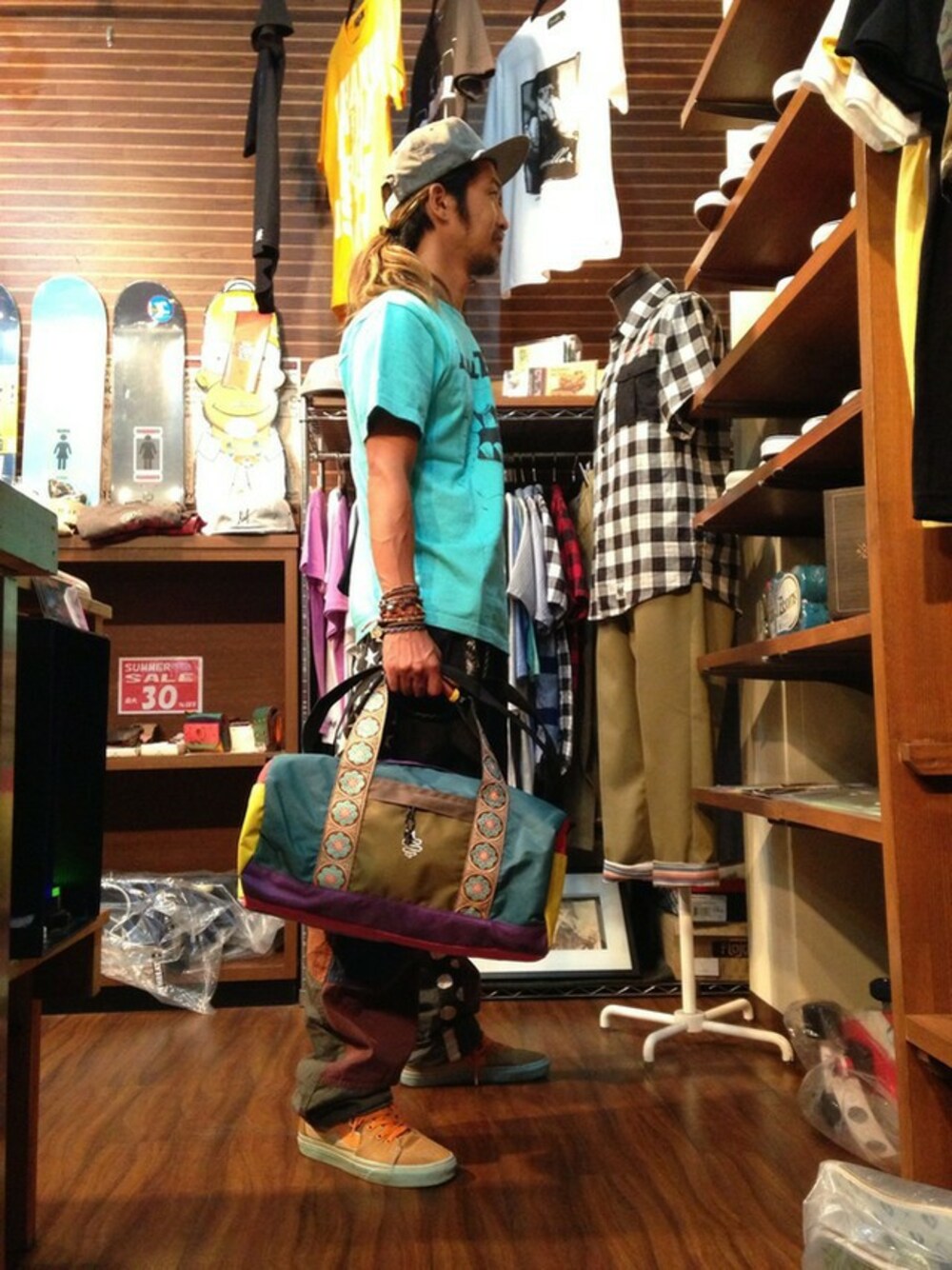 グリーン系のTシャツ/カットソー、グリーン系のボストンバッグ、ブルー系のキャップを着用したメンズの夏コーディネートの1枚目の写真