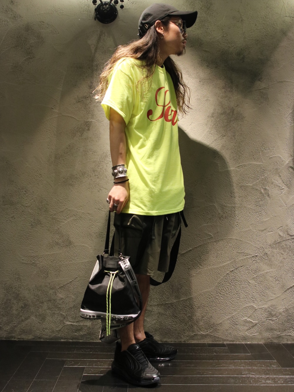 イエロー系のTシャツ/カットソー、ブラック系のショルダーバッグ、ブラック系のスニーカーを着用したメンズの春コーディネートの1枚目の写真