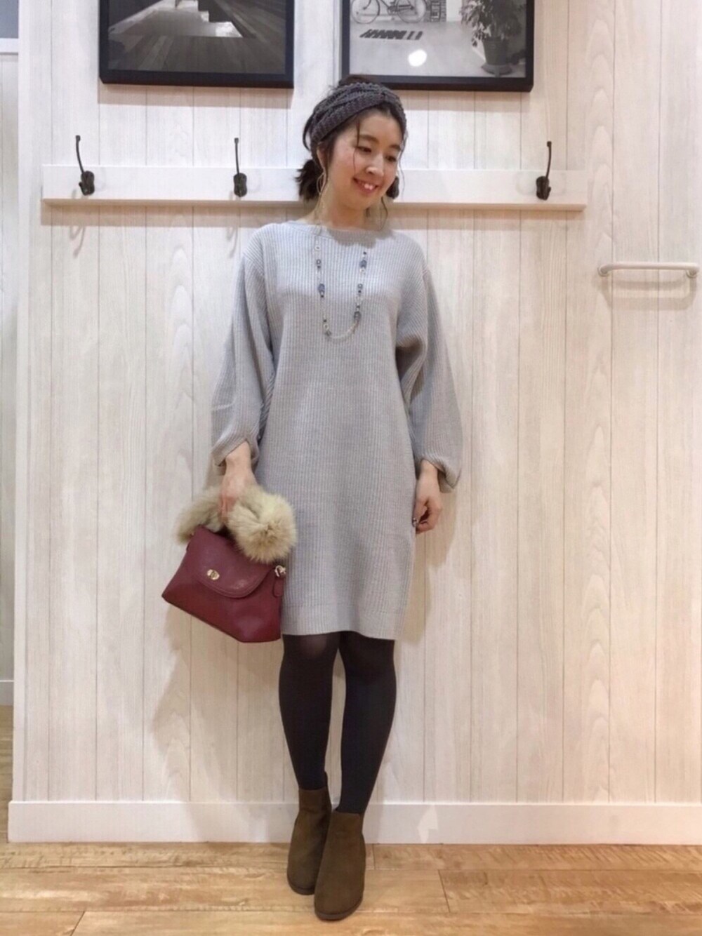 レッド系のショルダーバッグ、ブラウン系のブーツ、グレー系のワンピースを着用したレディースの冬コーディネートの1枚目の写真