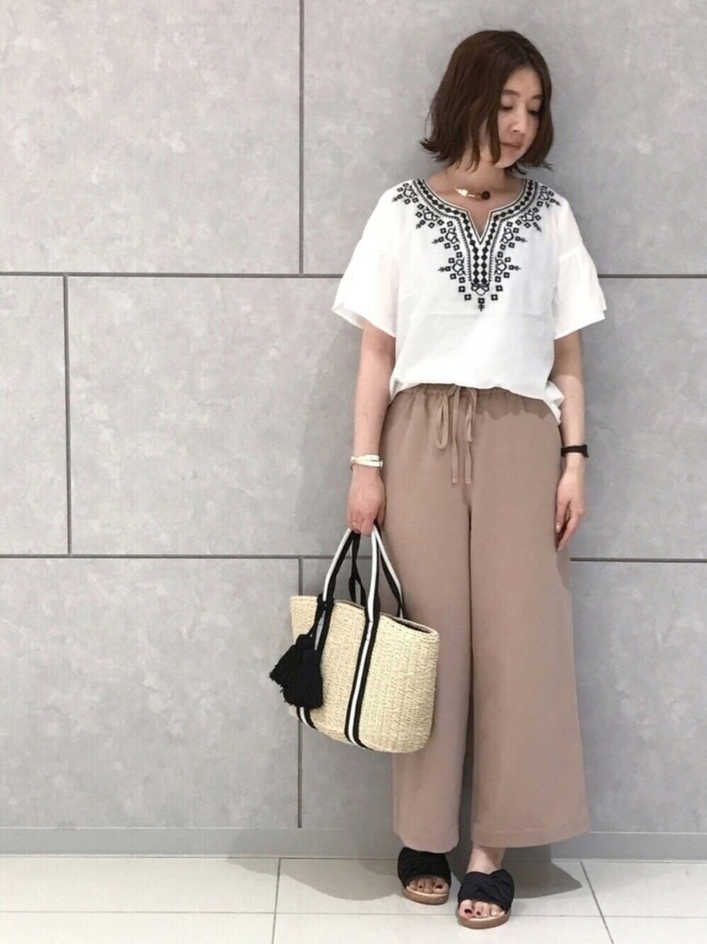 ブラック系のトートバッグ、ブラック系のサンダル、グレー系のタンクトップを着用したレディースの春コーディネートの1枚目の写真