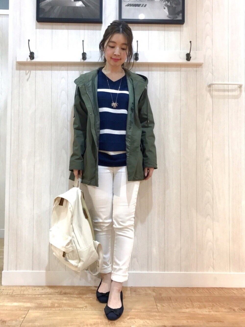 グリーン系のミリタリージャケット、ブルー系のニット/セーター、ホワイト系のデニムパンツを着用したレディースの春コーディネートの1枚目の写真