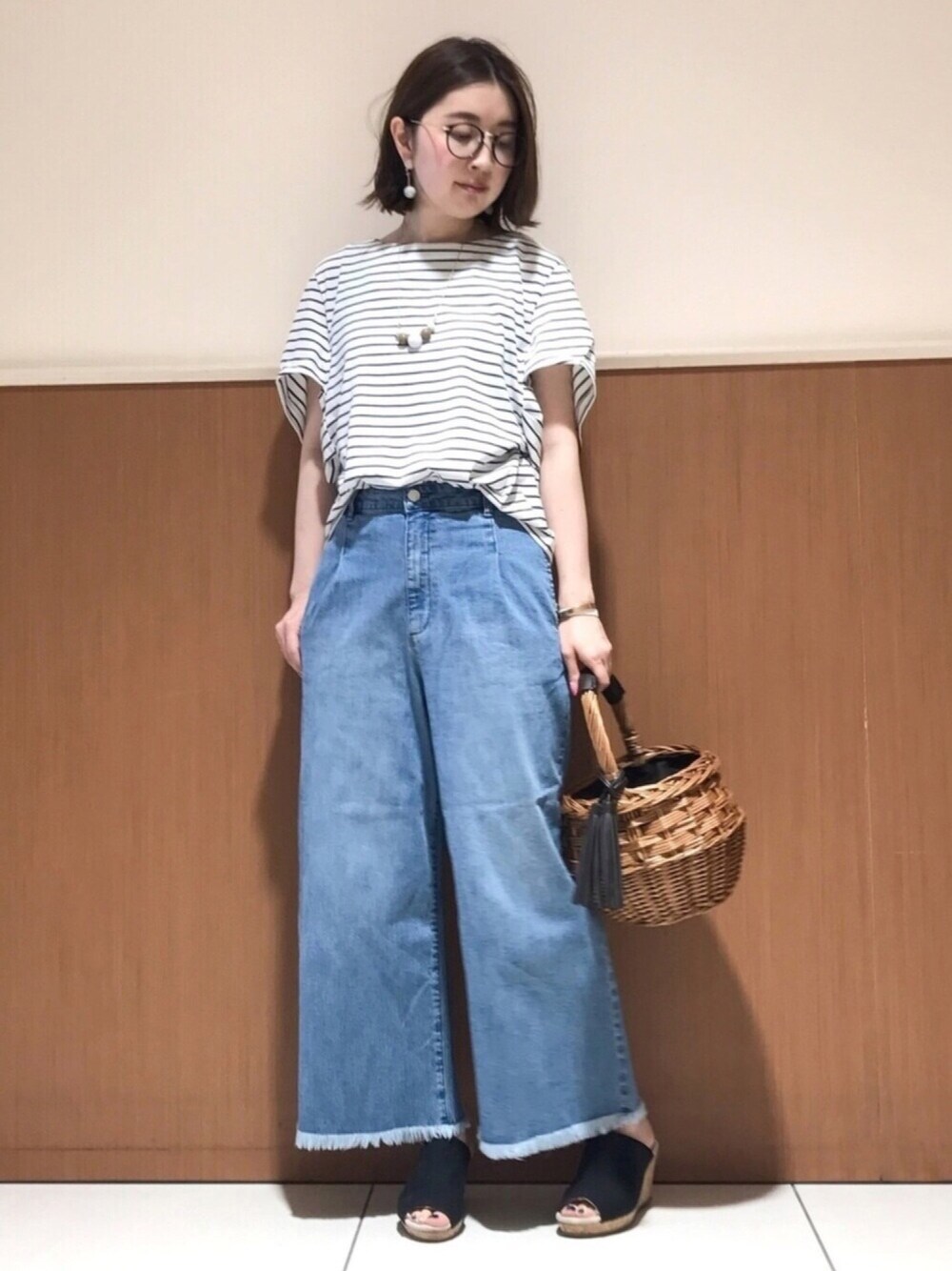 ブラウン系のハンドバッグ、ブラック系のサンダル、ブラック系のTシャツ/カットソーを着用したレディースの春コーディネートの1枚目の写真