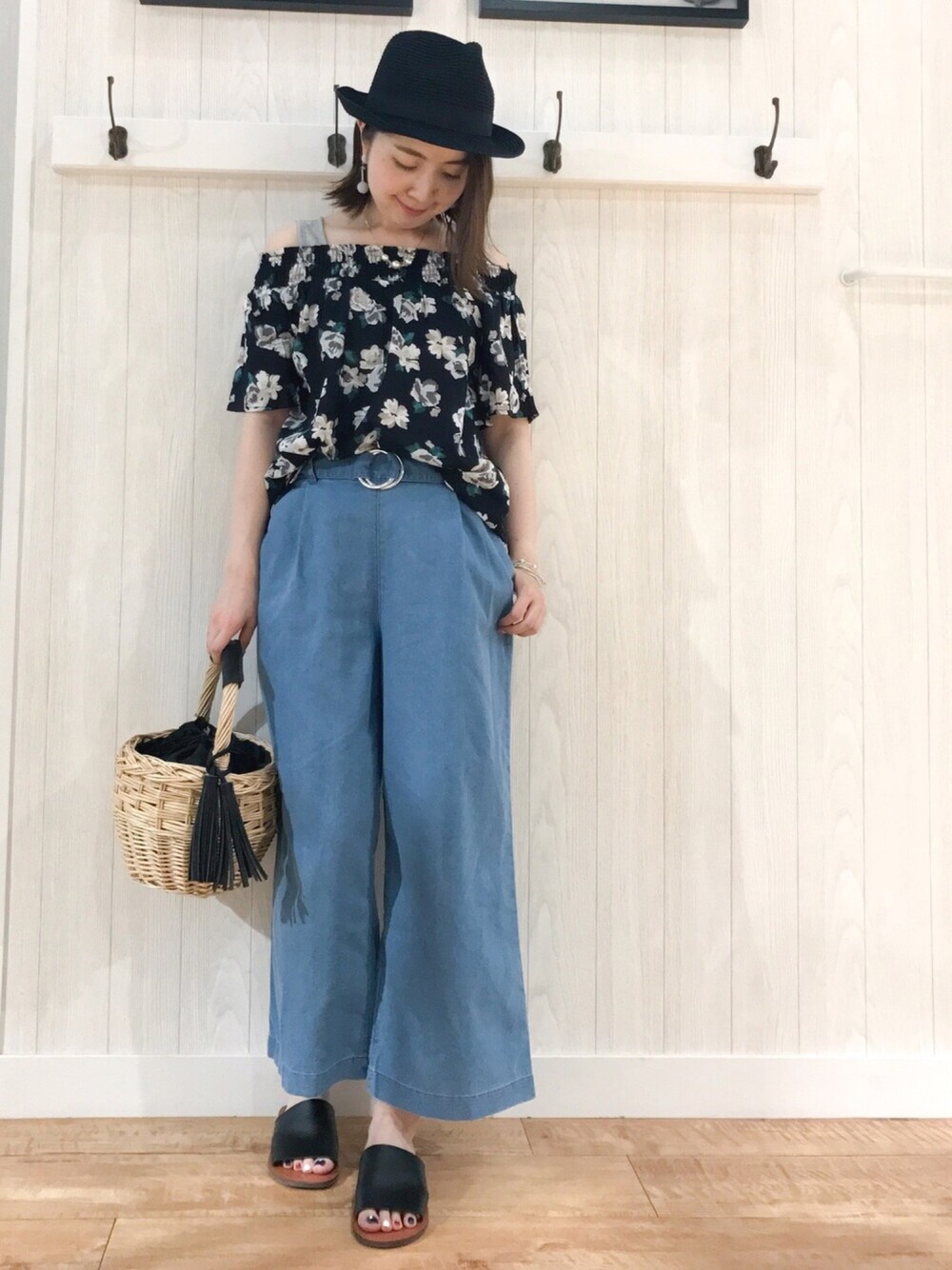 ブラウン系のハンドバッグ、ブラック系のサンダル、ブルー系のデニムパンツを着用したレディースの夏コーディネートの1枚目の写真