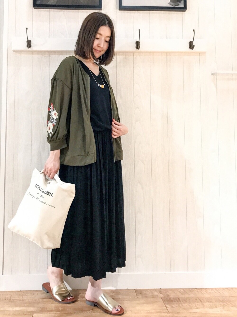 グリーン系のカーディガン/ボレロ、ブラック系のワンピース、ホワイト系のショルダーバッグを着用したレディースの夏コーディネートの1枚目の写真