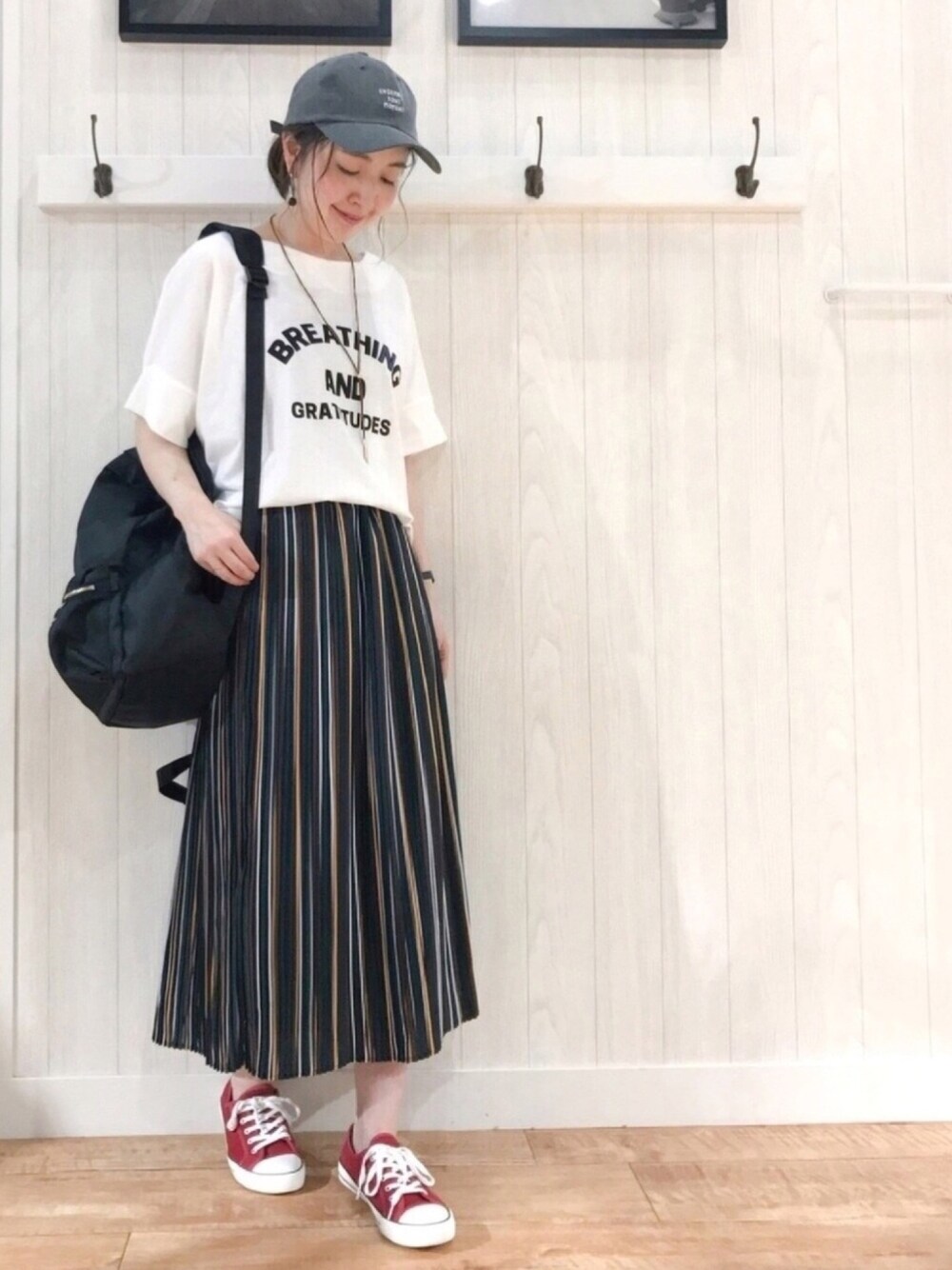 ホワイト系のTシャツ/カットソー、グリーン系のスカート、ブラック系のバックパック/リュックを着用したレディースの夏コーディネートの1枚目の写真