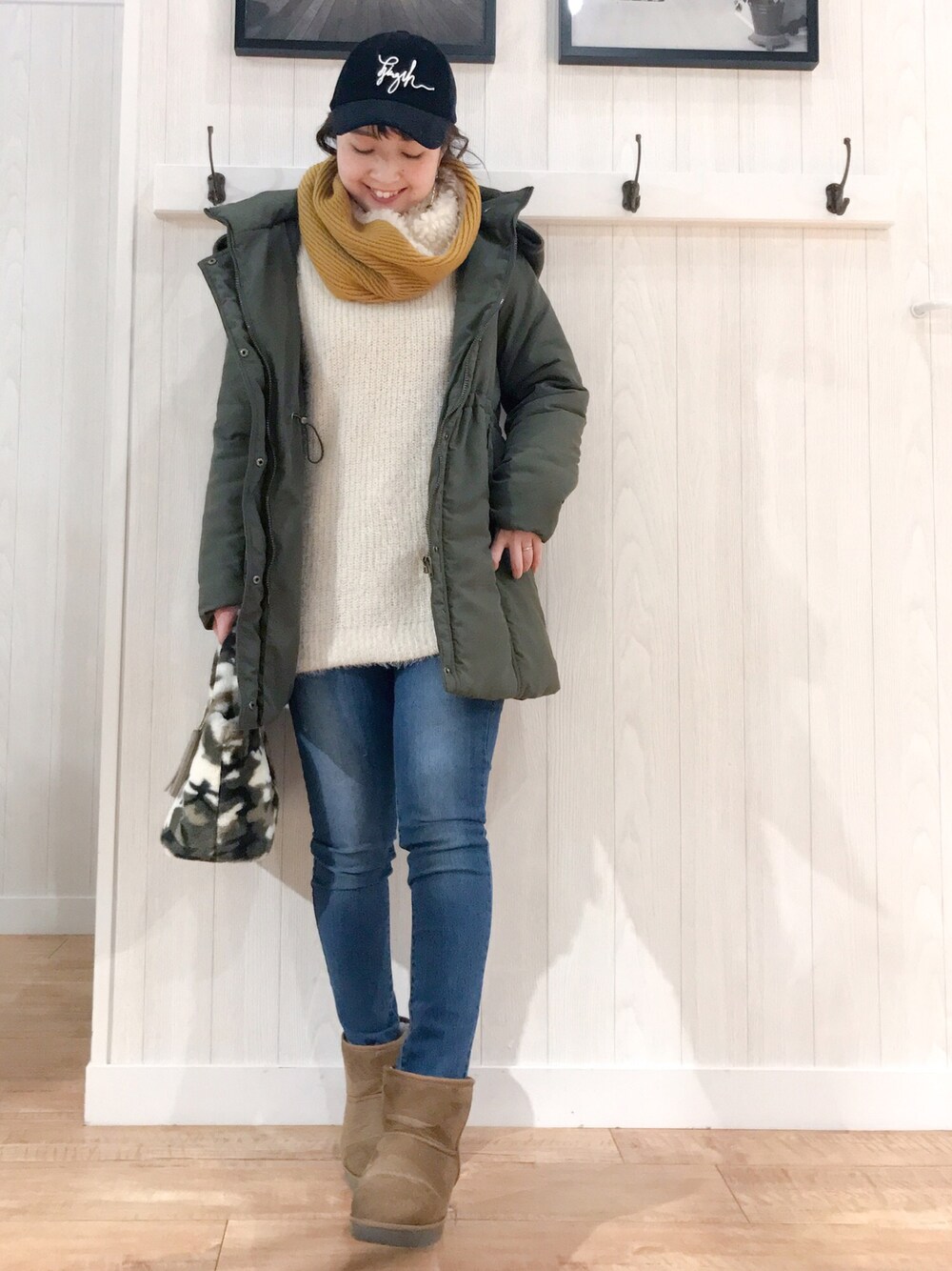 グリーン系のダウンジャケット/コート、ピンク系のニット/セーター、ブルー系のデニムパンツを着用したレディースの冬コーディネートの1枚目の写真