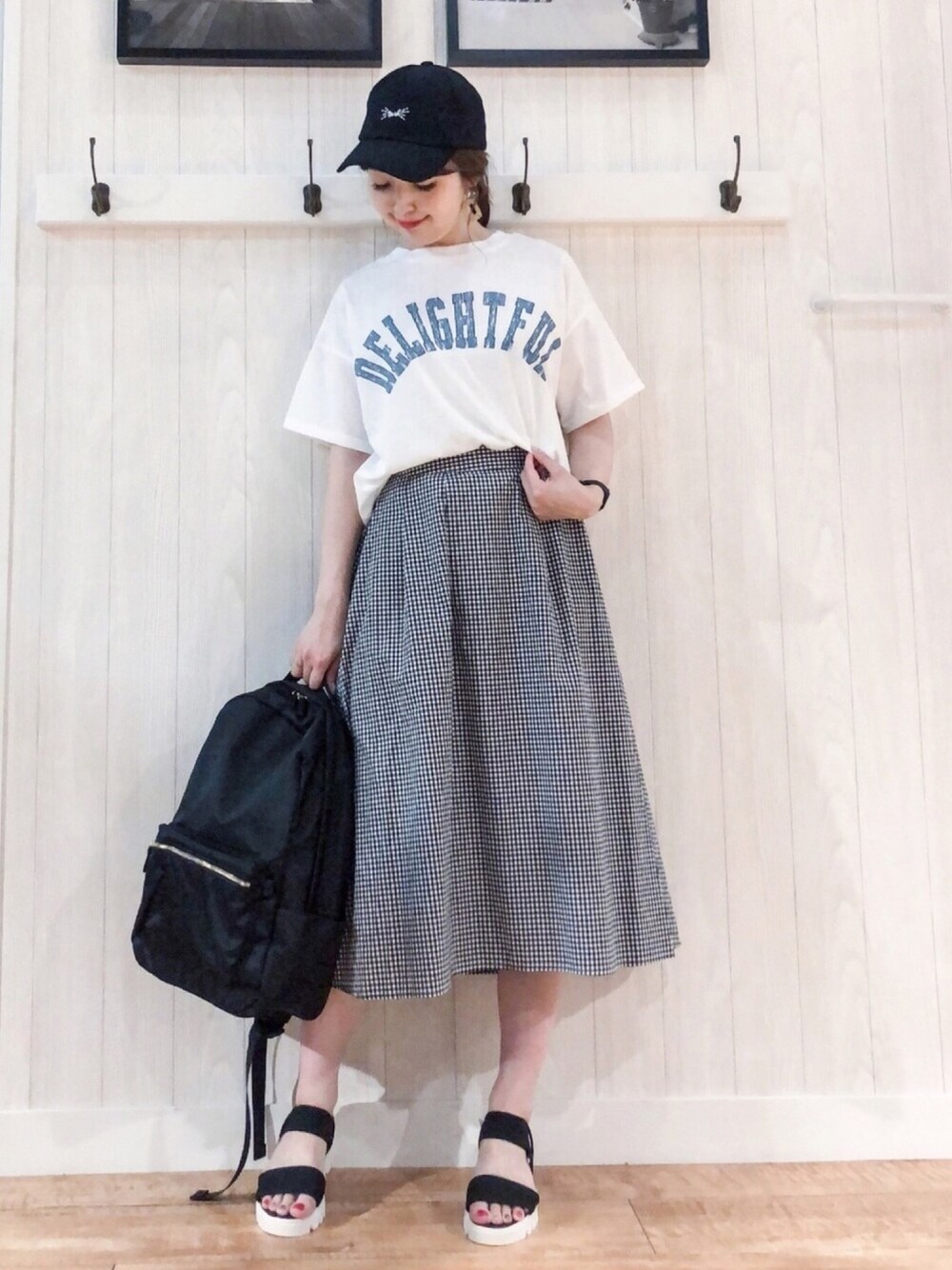 ホワイト系のTシャツ/カットソー、ブラック系のスカート、ブラック系のバックパック/リュックを着用したレディースの夏コーディネートの1枚目の写真