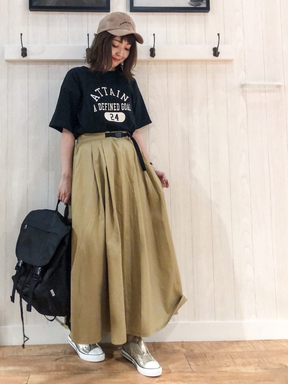 ブラック系のTシャツ/カットソー、ベージュ系のスカート、ブラック系のバックパック/リュックを着用したレディースの夏コーディネートの1枚目の写真