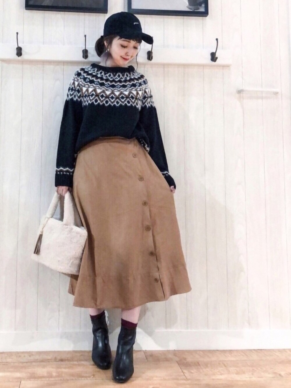 ブラック系のニット/セーター、イエロー系のスカート、ブラック系のブーツを着用したレディースの秋コーディネートの1枚目の写真