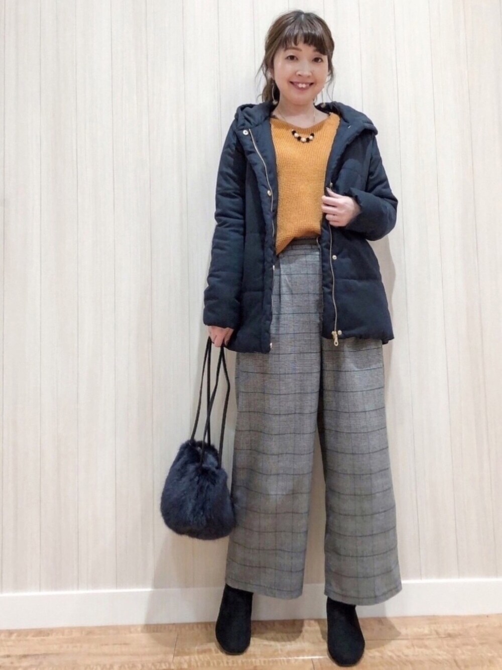 イエロー系のニット/セーター、グレー系のTシャツ/カットソー、ブラック系のその他パンツを着用したレディースの冬コーディネートの1枚目の写真