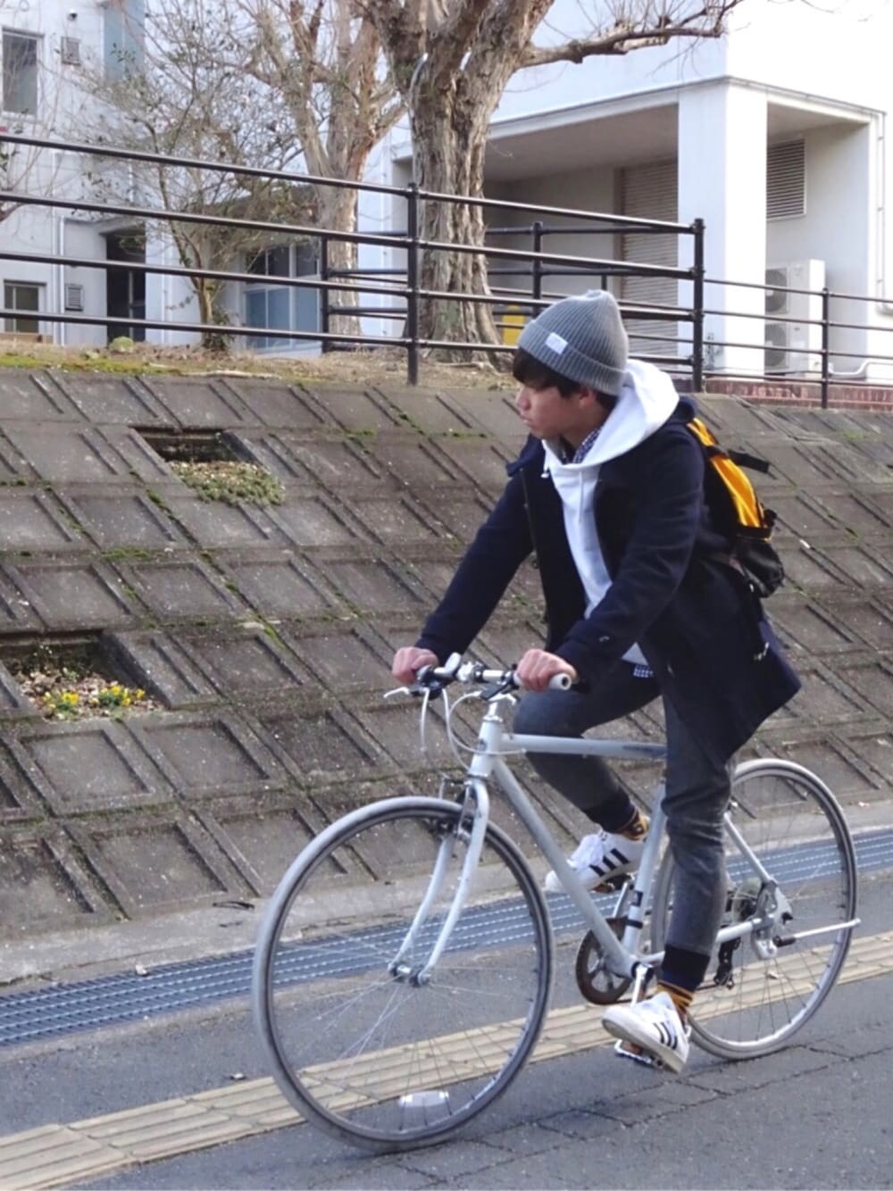 イエロー系のバックパック/リュック、ホワイト系のスニーカー、ブルー系のシャツ/ブラウスを着用したメンズの冬コーディネートの1枚目の写真