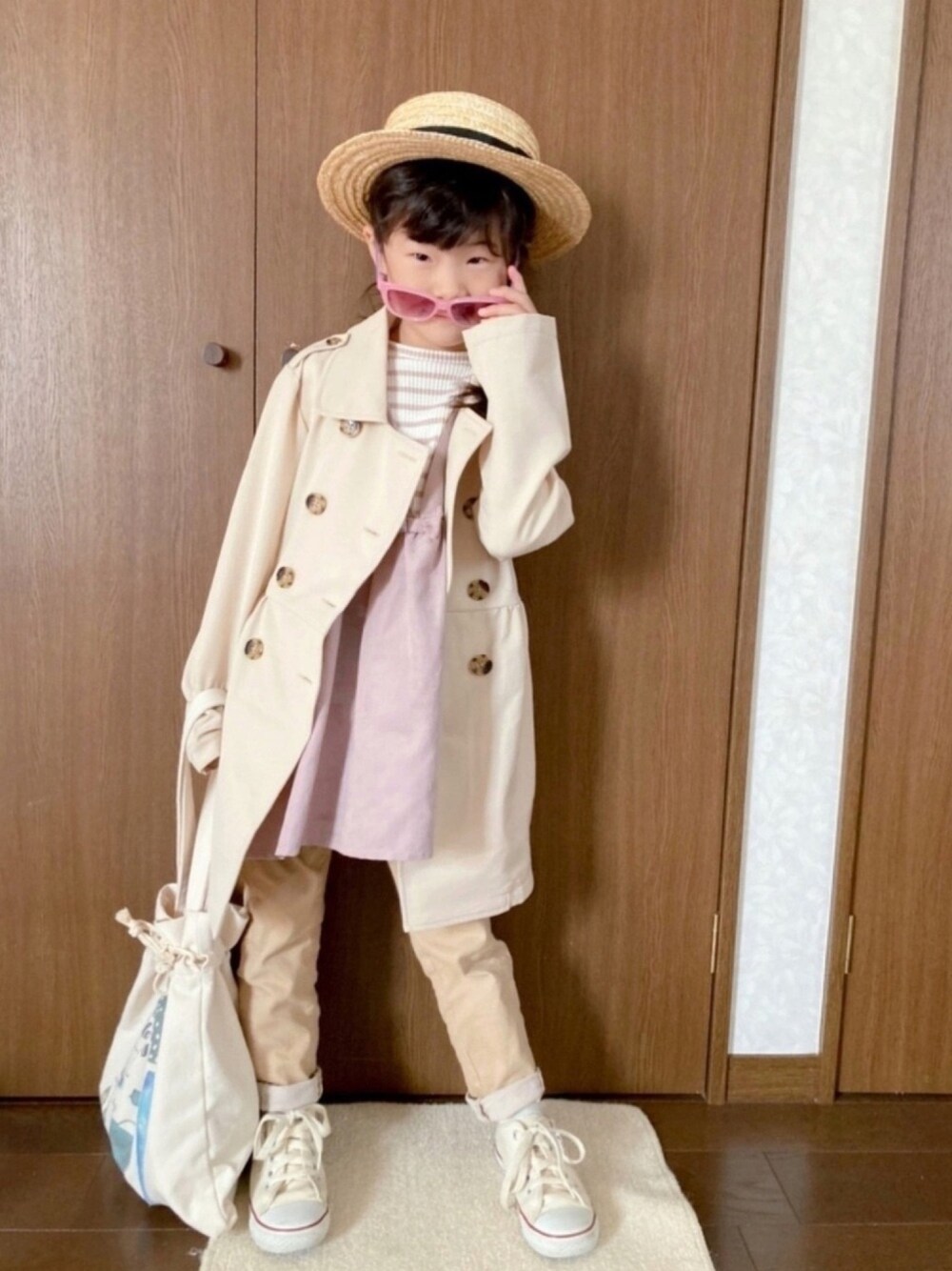 ベージュ系のトレンチコート、ピンク系のワンピース、ベージュ系のその他パンツを着用したキッズの春コーディネートの1枚目の写真