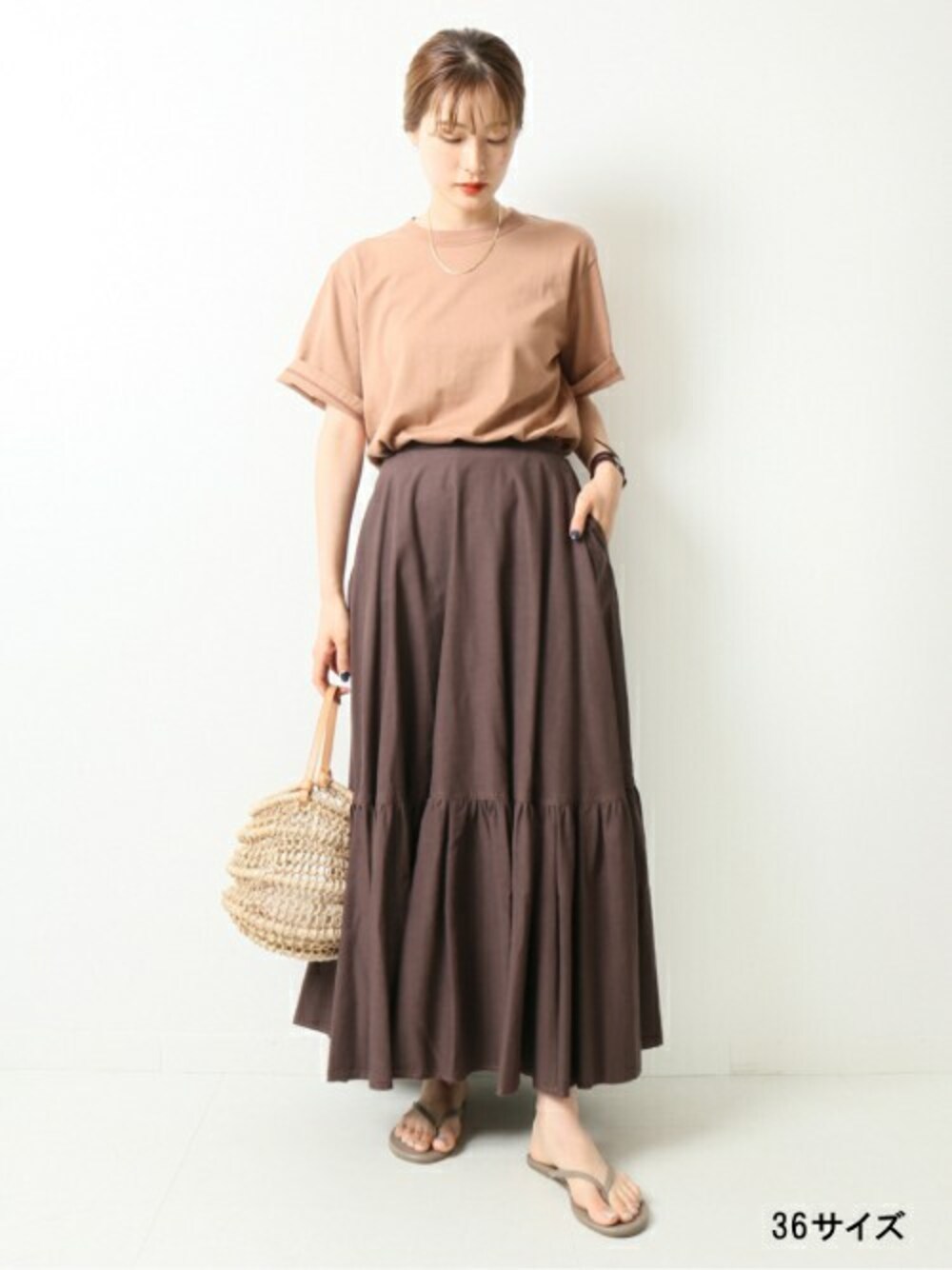 ブラウン系のスカート、ベージュ系のTシャツ/カットソーを着用したレディースの夏コーディネートの1枚目の写真