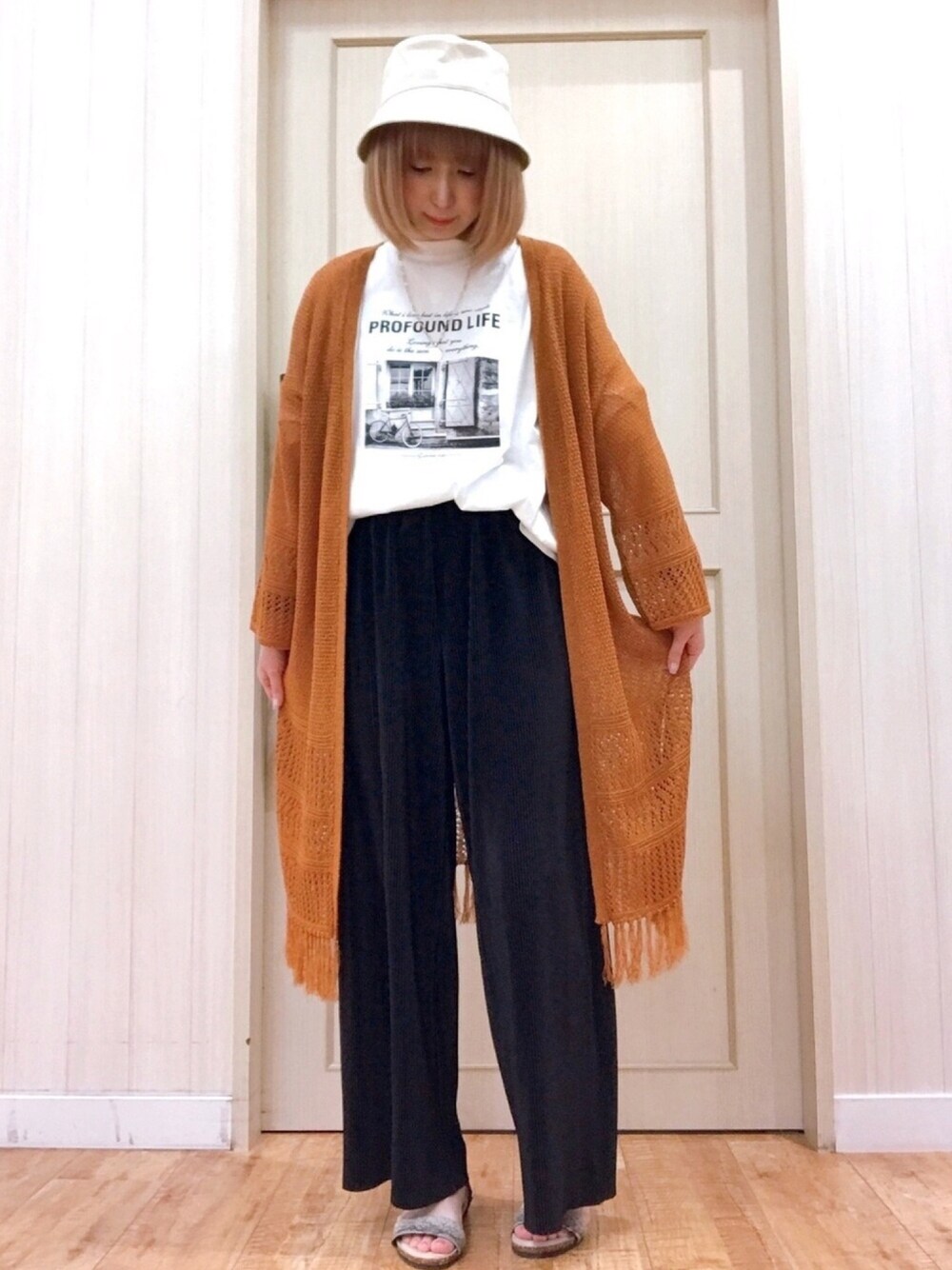 オレンジ系のカーディガン/ボレロ、ホワイト系のTシャツ/カットソー、ブラック系のその他パンツを着用したレディースの春コーディネートの1枚目の写真