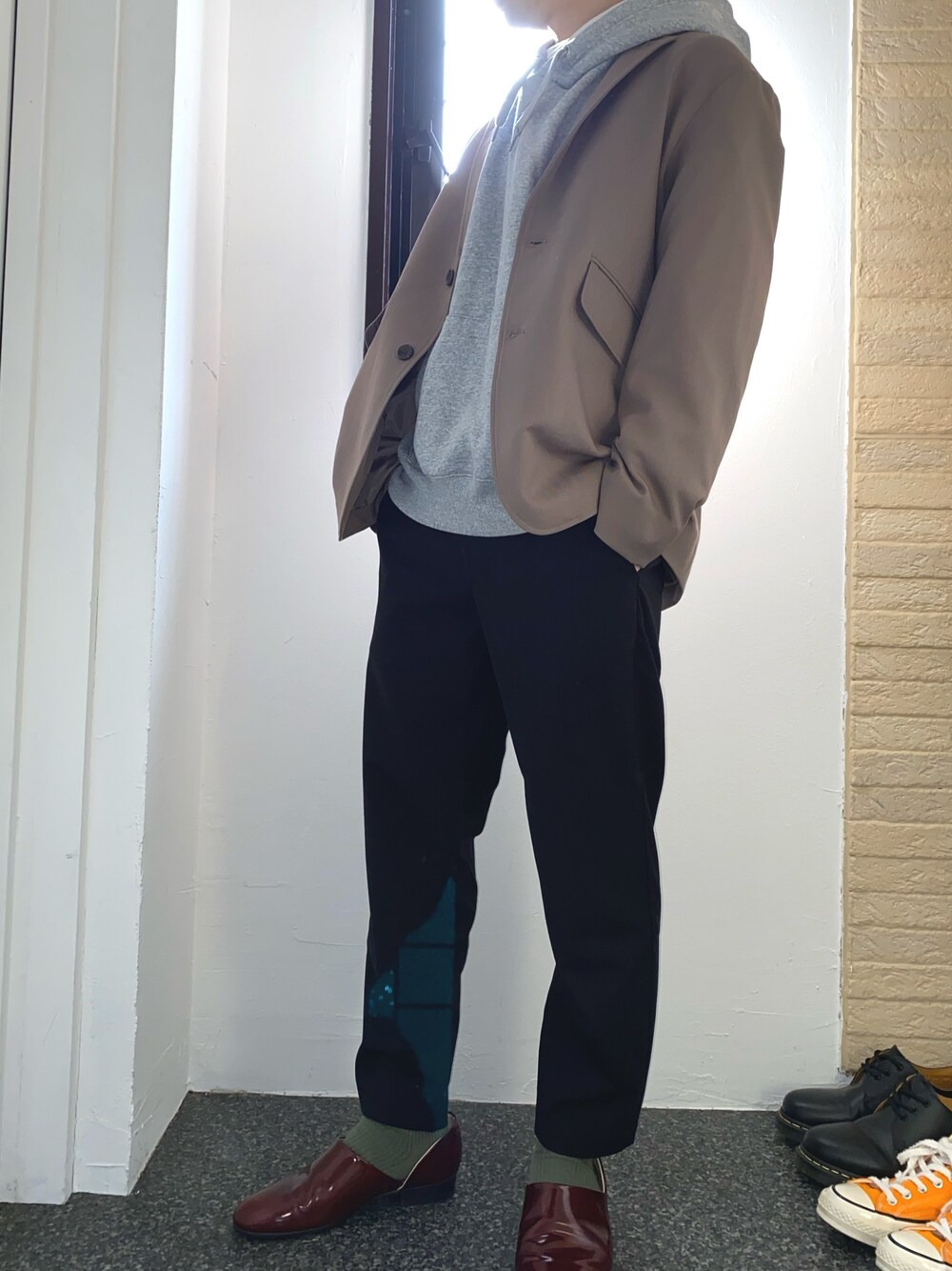 ベージュ系のセットアップ、グレー系のパーカー、ブラック系のスラックスを着用したメンズの春コーディネートの1枚目の写真